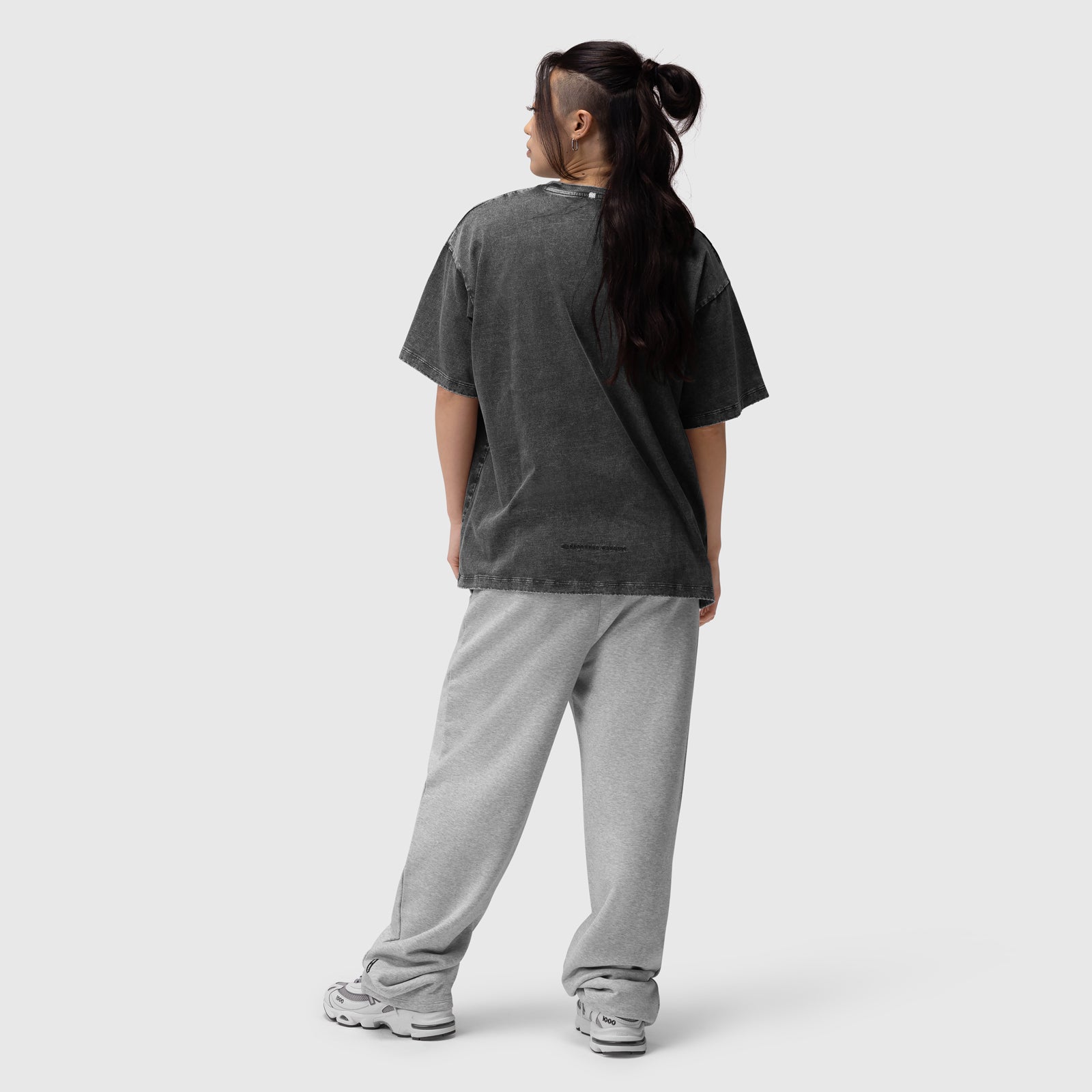 Distressed relaxed tee in black worn with grey joggers, back view