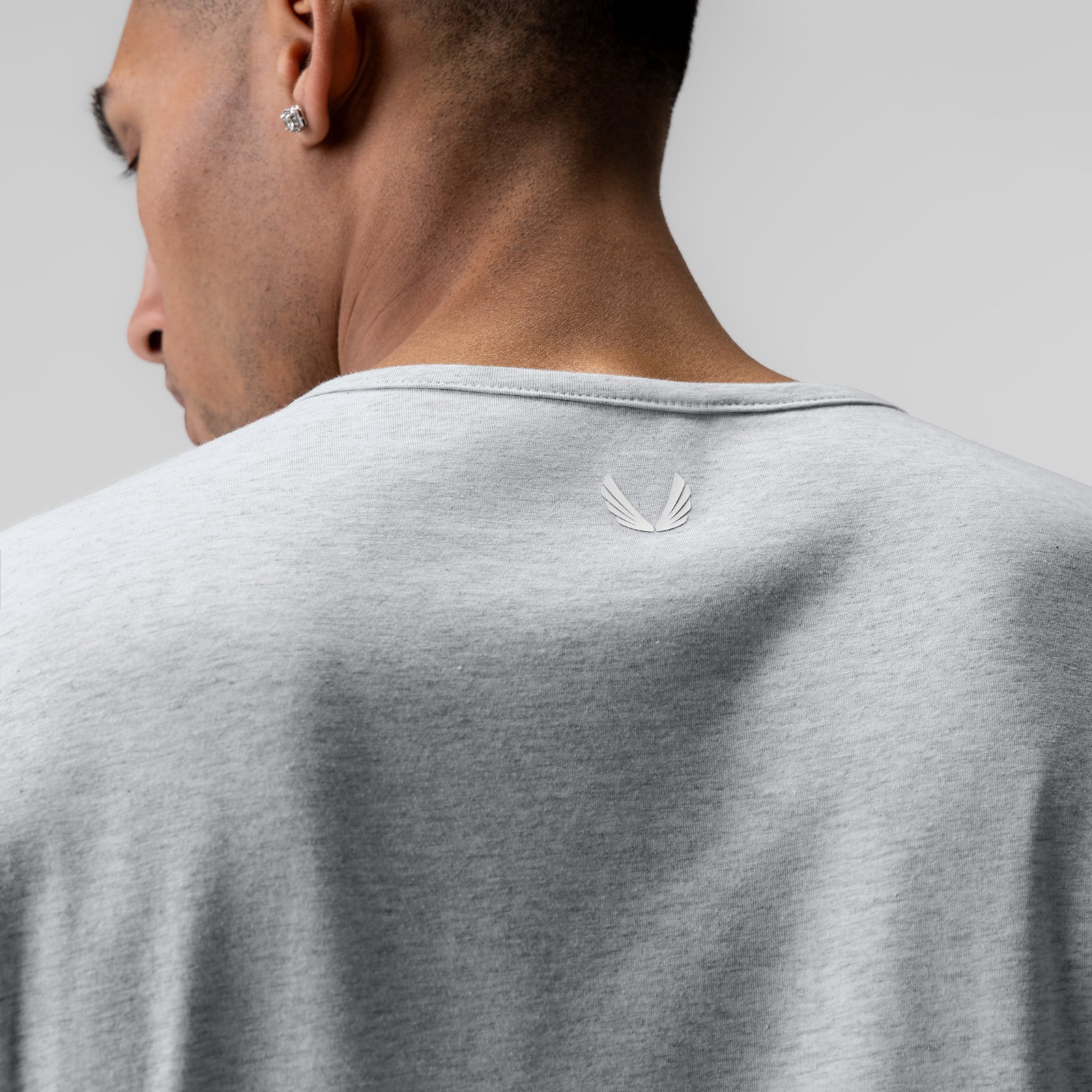 Heather grey long sleeve shirt on model, back view showing tonal logo detail