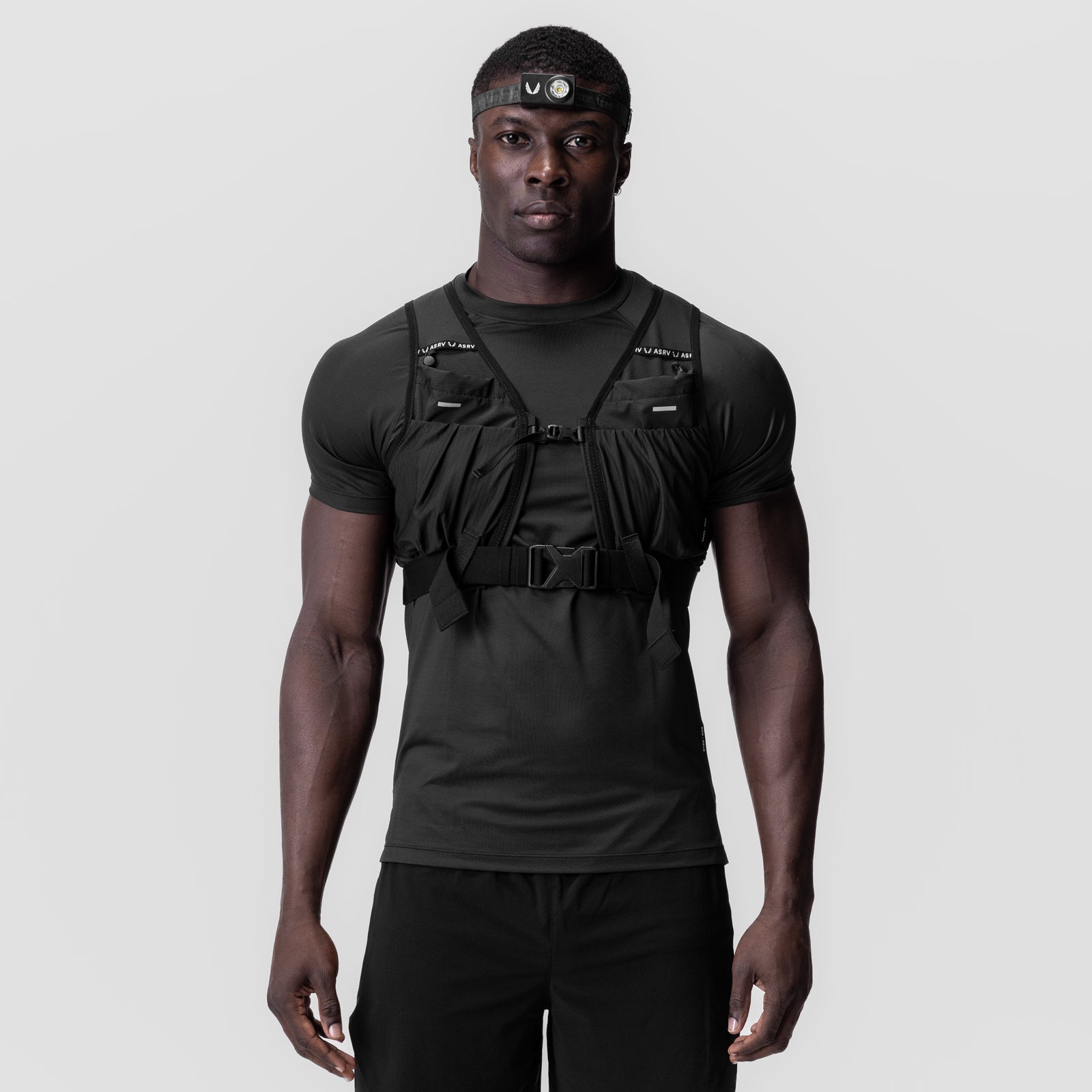 Black tactical vest worn over black t-shirt with headlamp, front view on model