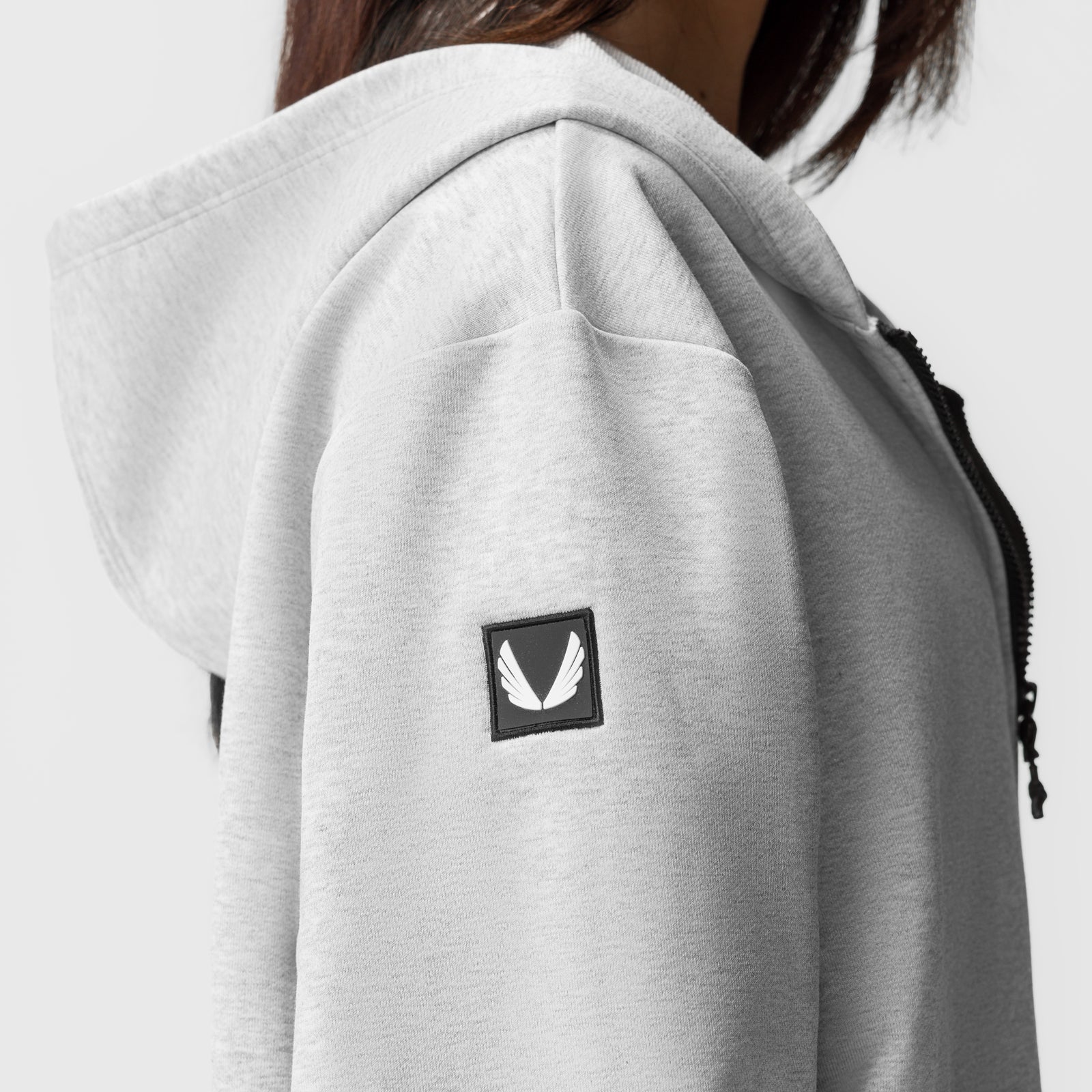 Heather grey oversized zip hoodie worn by model, rear view showing logo patch
