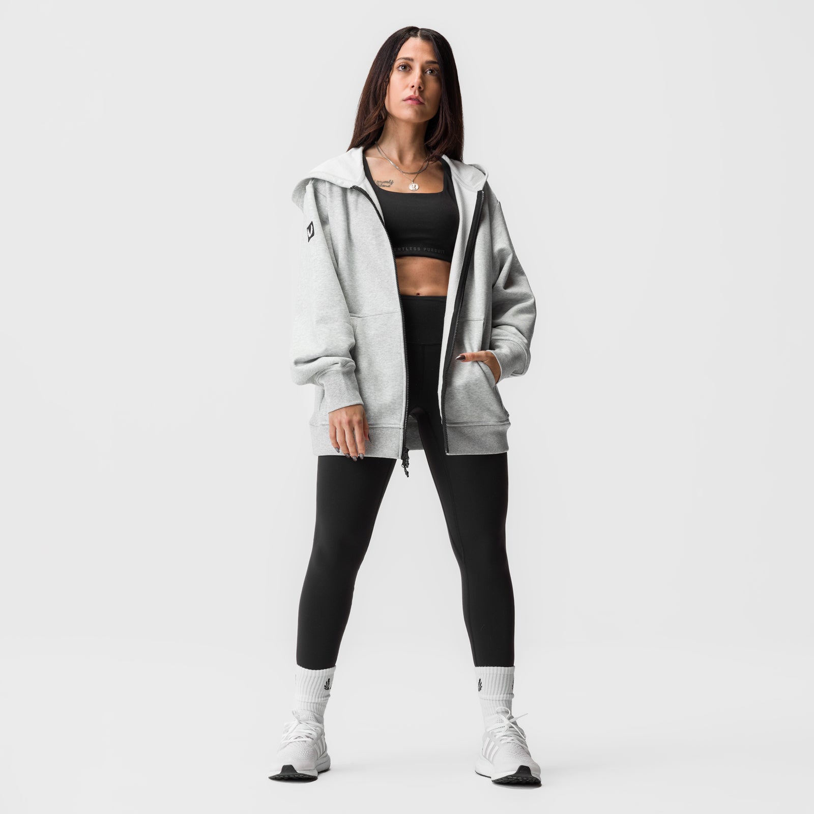 Heather grey oversized zip hoodie worn with black sports bra and leggings, white socks and sneakers