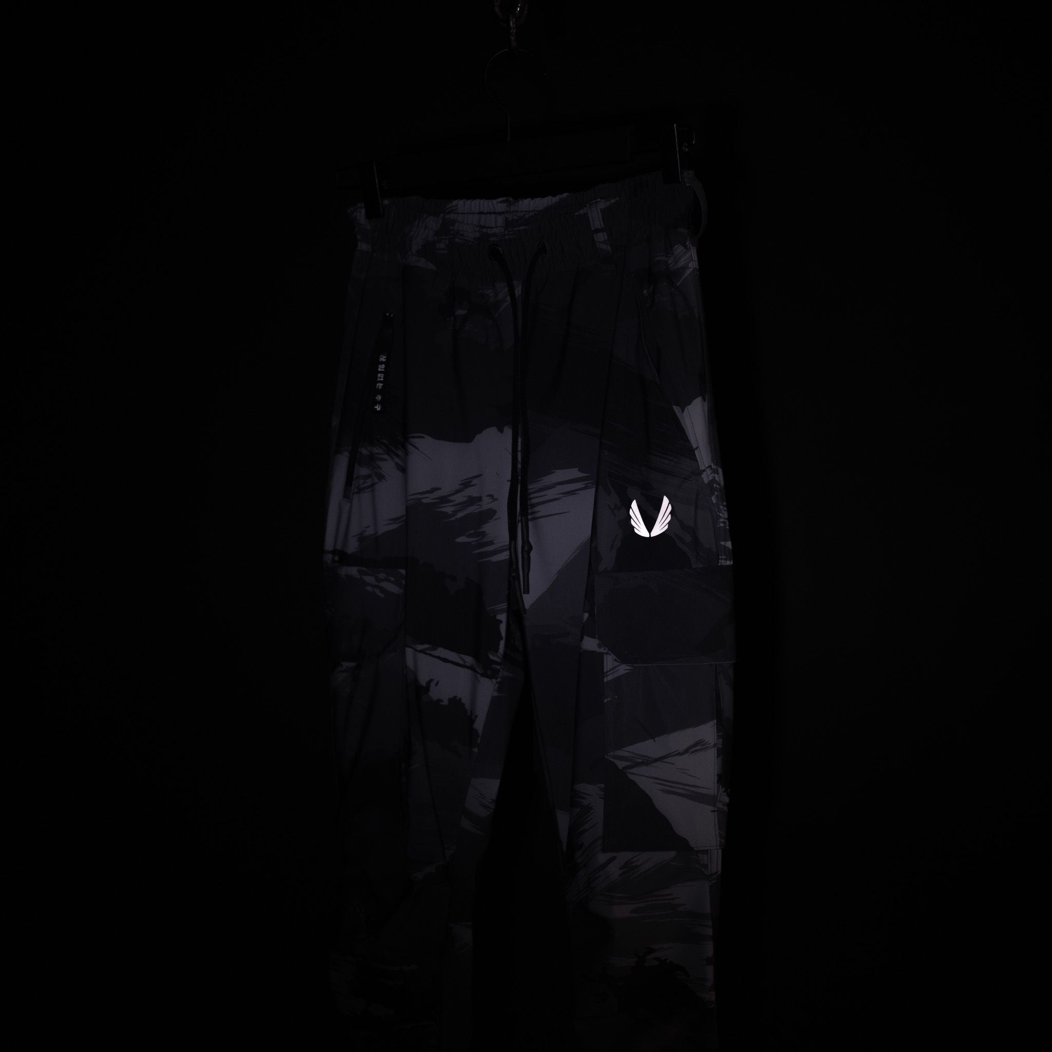 SM'20 Cargo High Rib pants in black with reflective logo, displayed on model against dark background