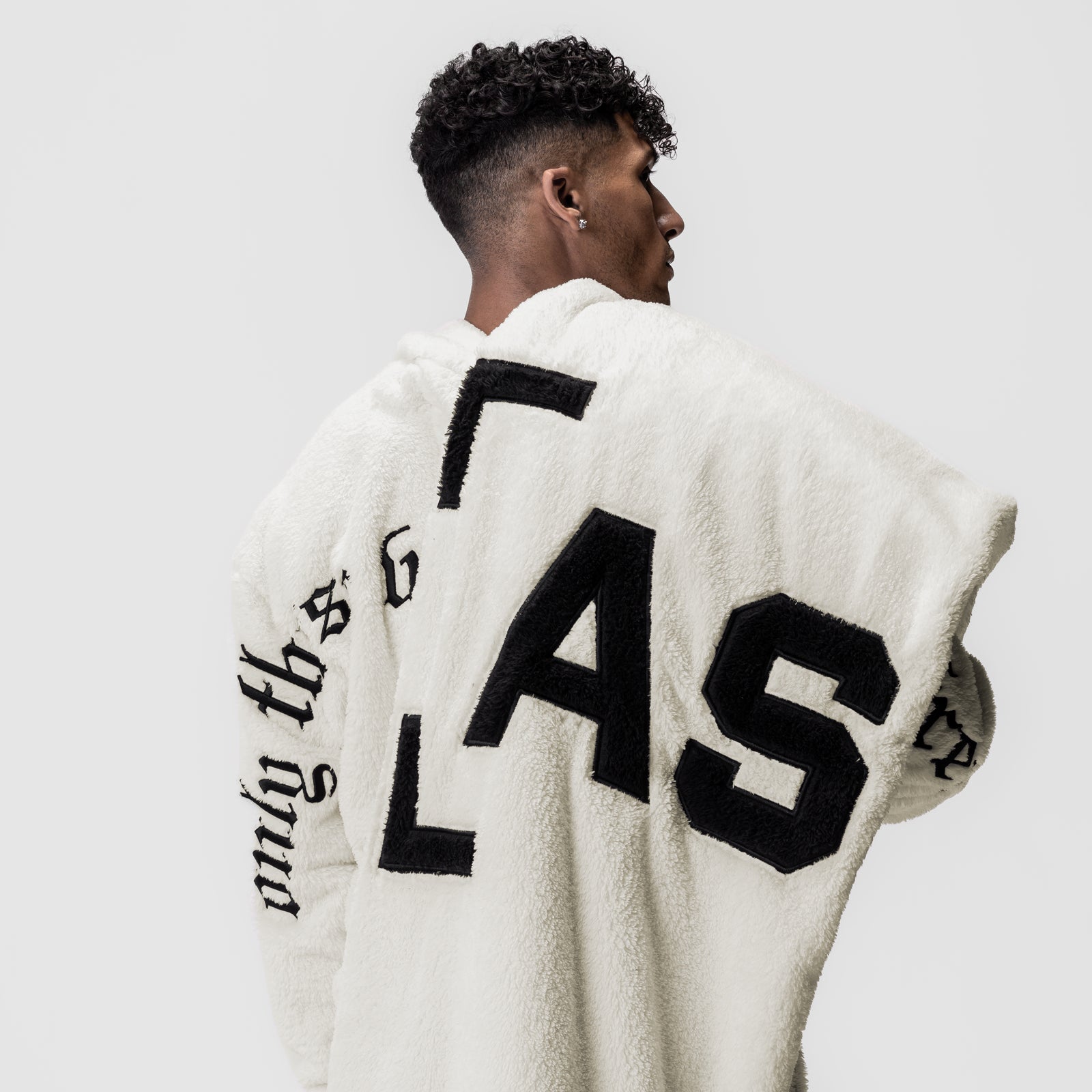 Sherpa Recovery Blanket in ivory cream with black lettering, worn by model showing back view