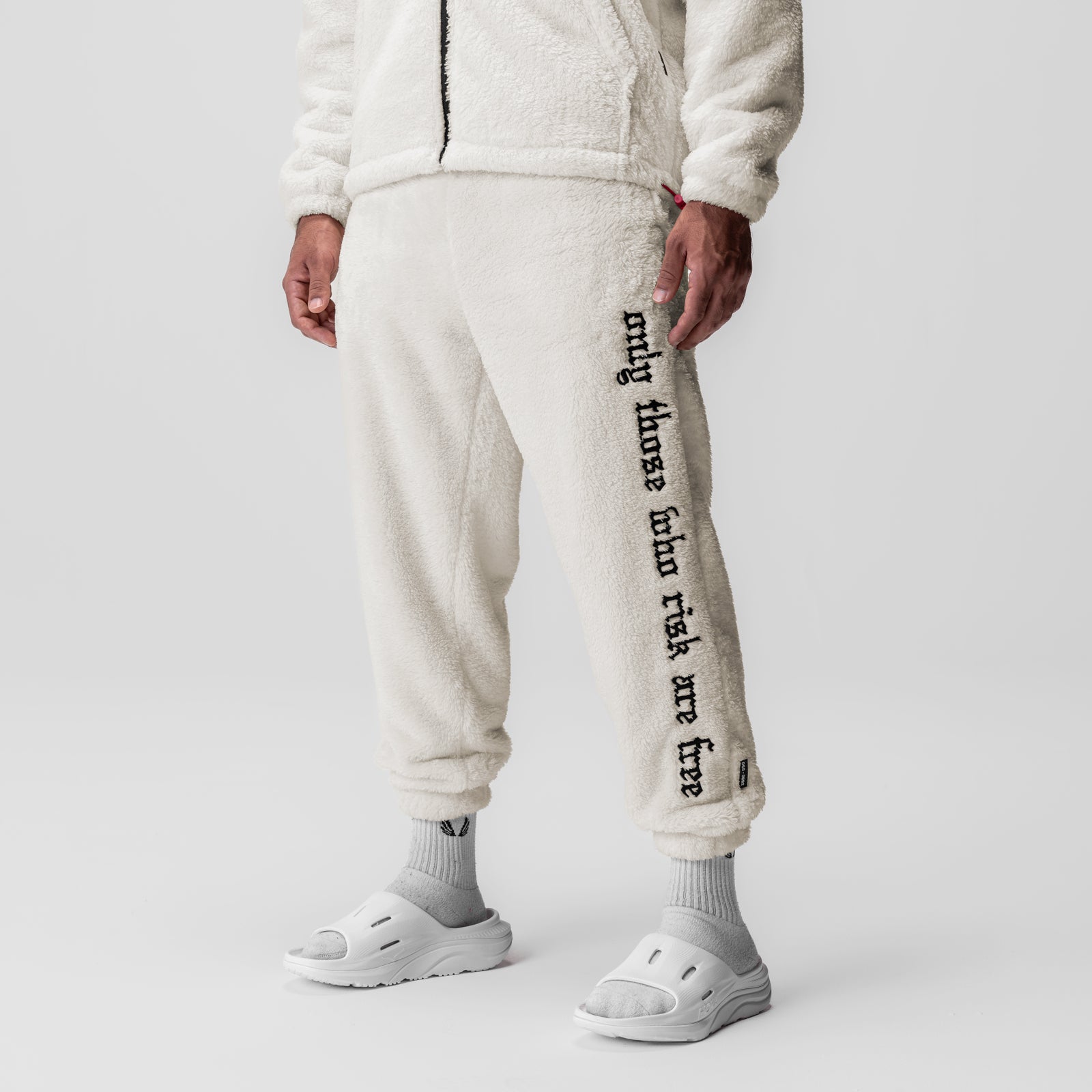 Sherpa Recovery Sweats in ivory cream with black text detail, worn by model, full-length front view