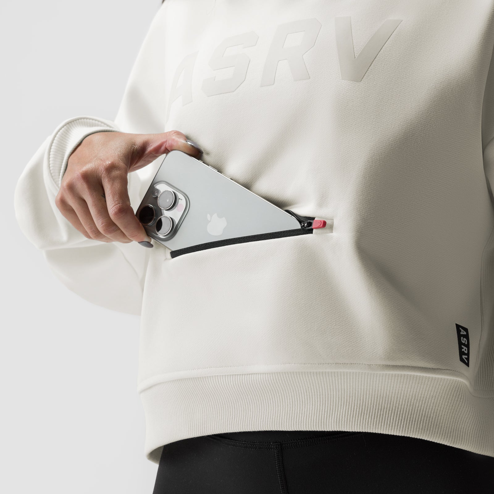 Ivory cream cropped hoodie worn by model holding smartphone with black shoulder strap