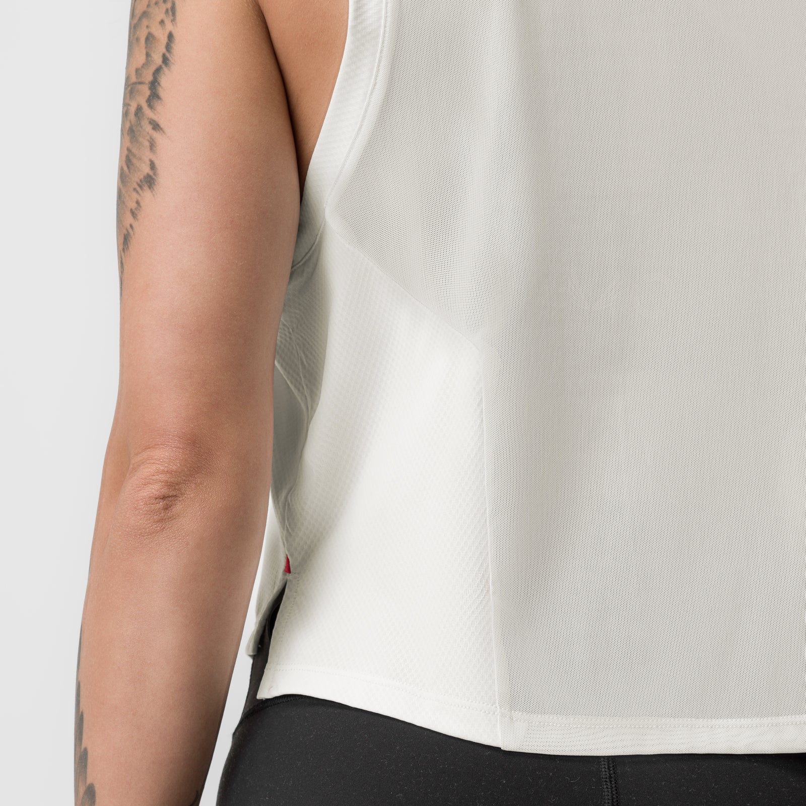 Ivory cream cropped training tank on model, side view showing fit and tattooed arm