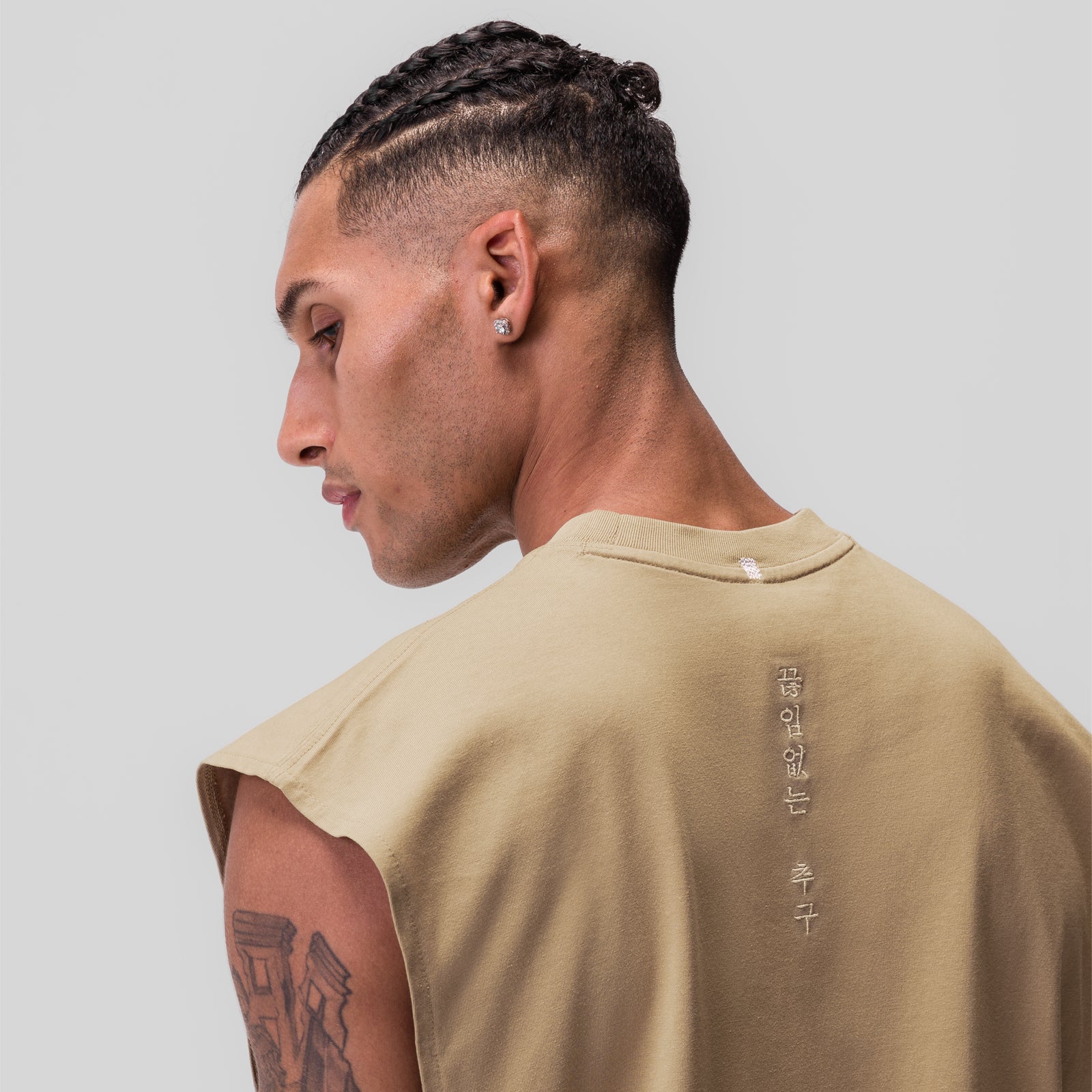 Tech Essential Rocker Cutoff in khaki, model wearing sleeveless tee showing back view with vertical text design