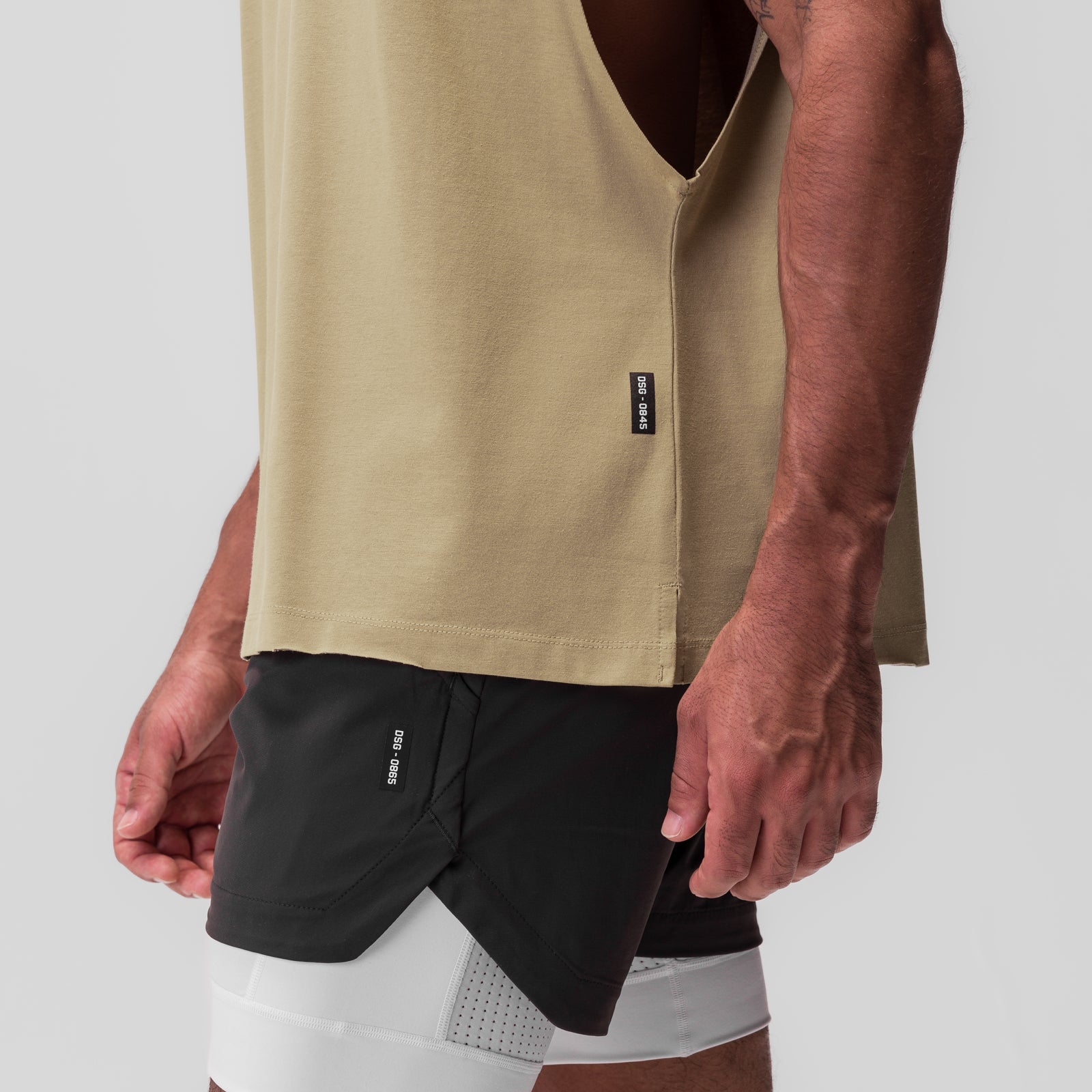 Tech Essential Rocker Cutoff tank in khaki worn with black shorts, front view on model