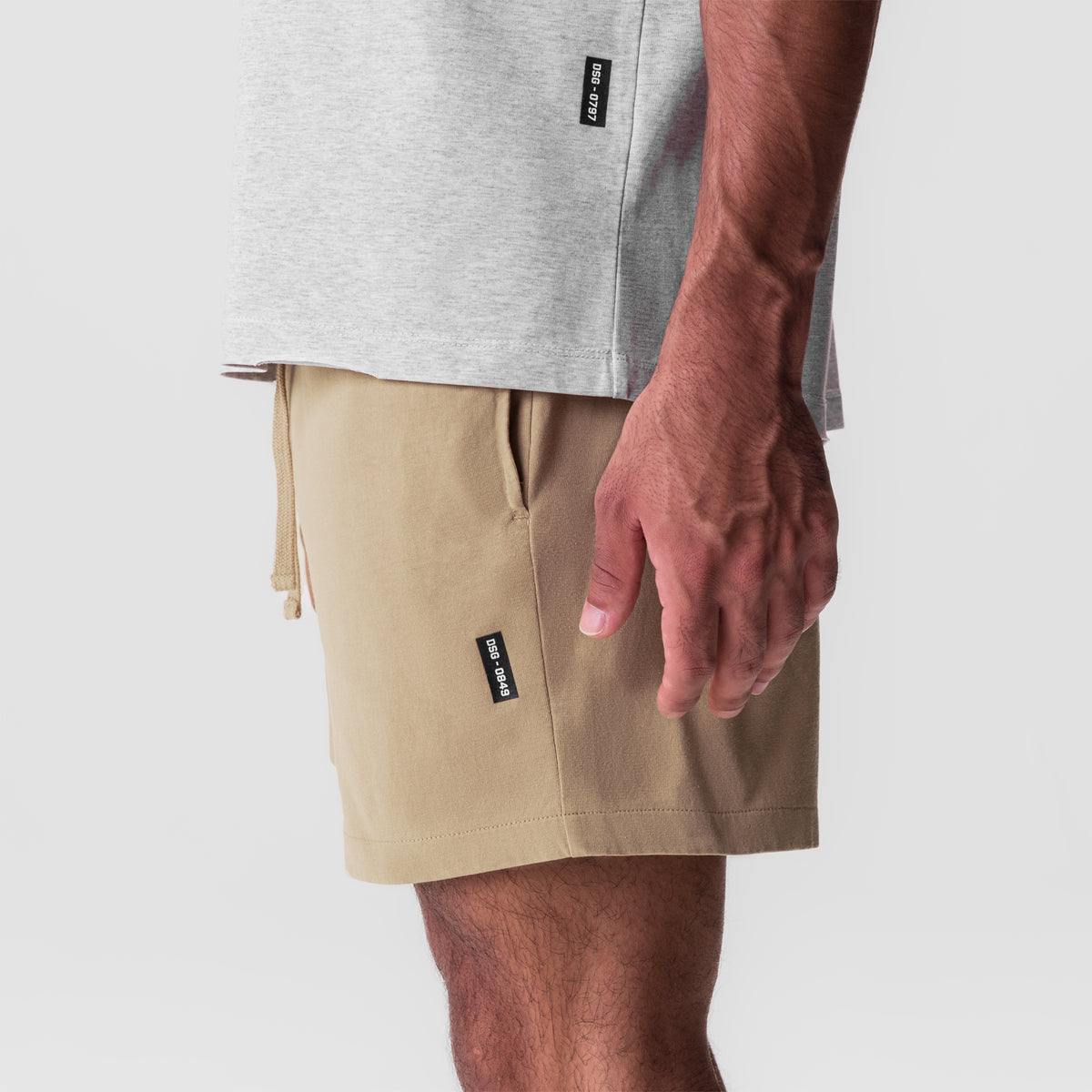 Tech Essential Sweat Short in khaki, worn by model with gray t-shirt, side view