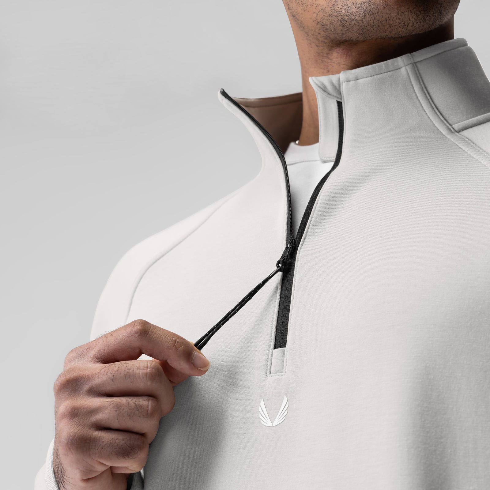 Dri-Core Quarter Zip in light grey, worn by model holding zipper detail