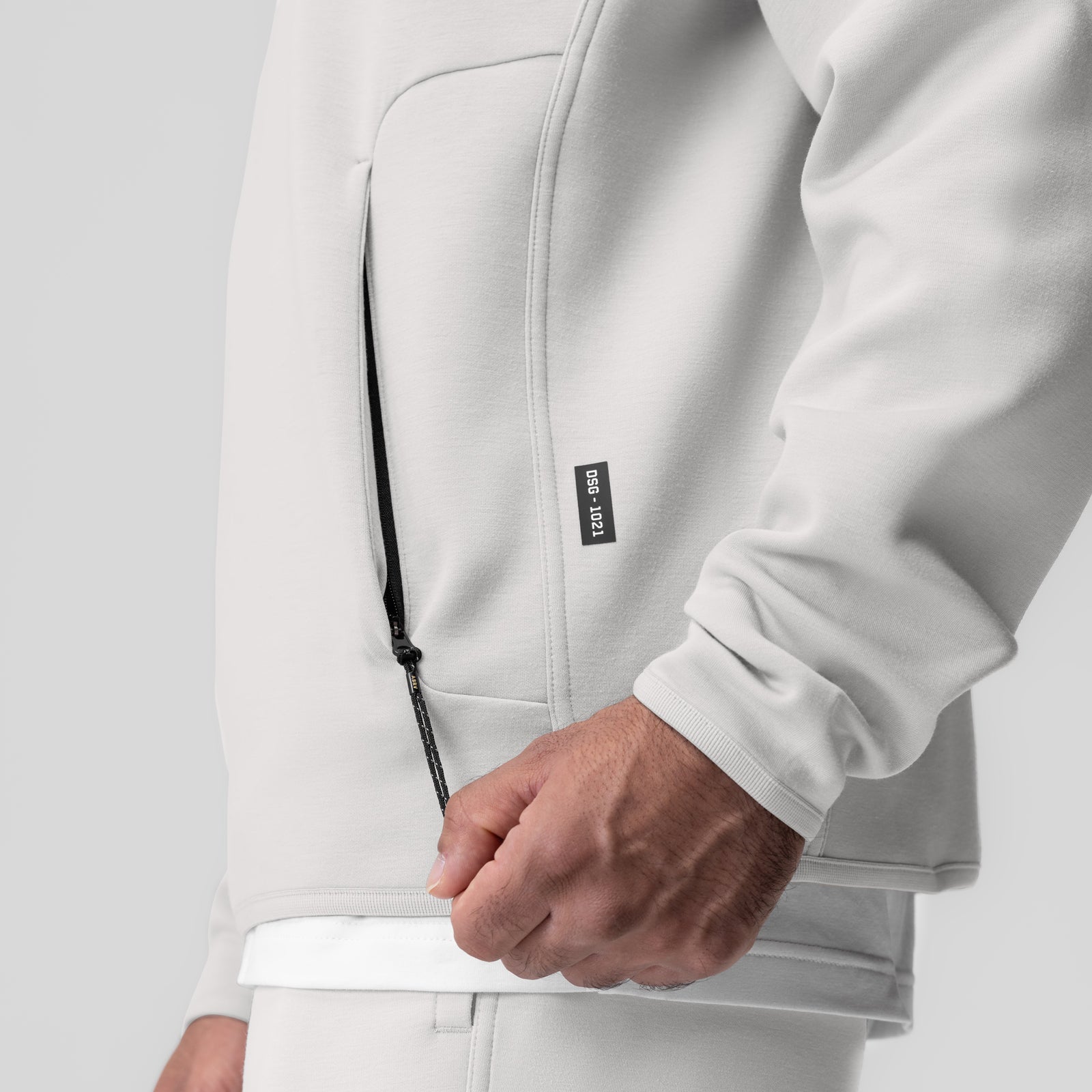 Dri-Core Quarter Zip in light grey worn by model, showing front zipper detail and hand placement
