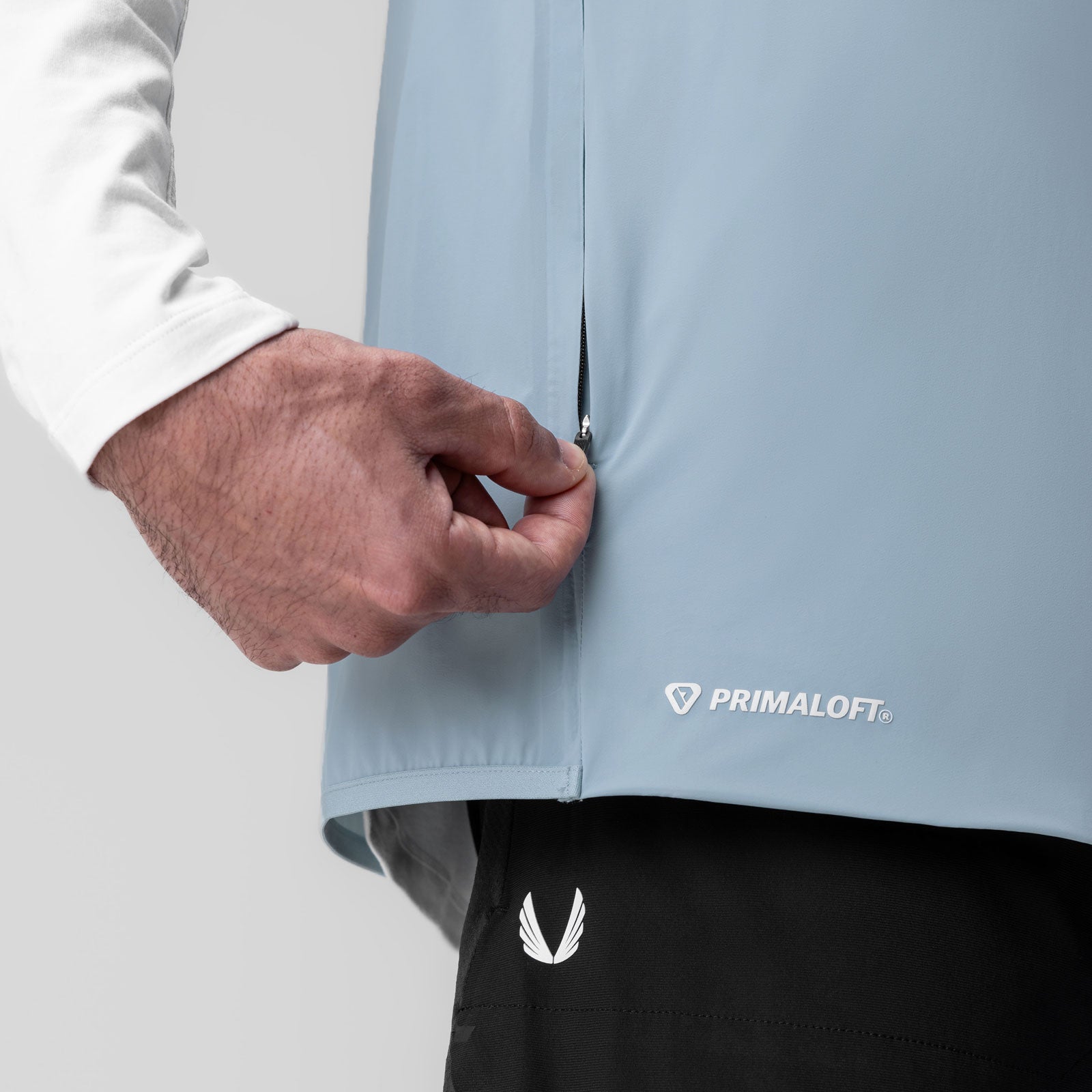 Aerotex PrimaLoft Run Vest in light sky, being held by model wearing white long sleeve