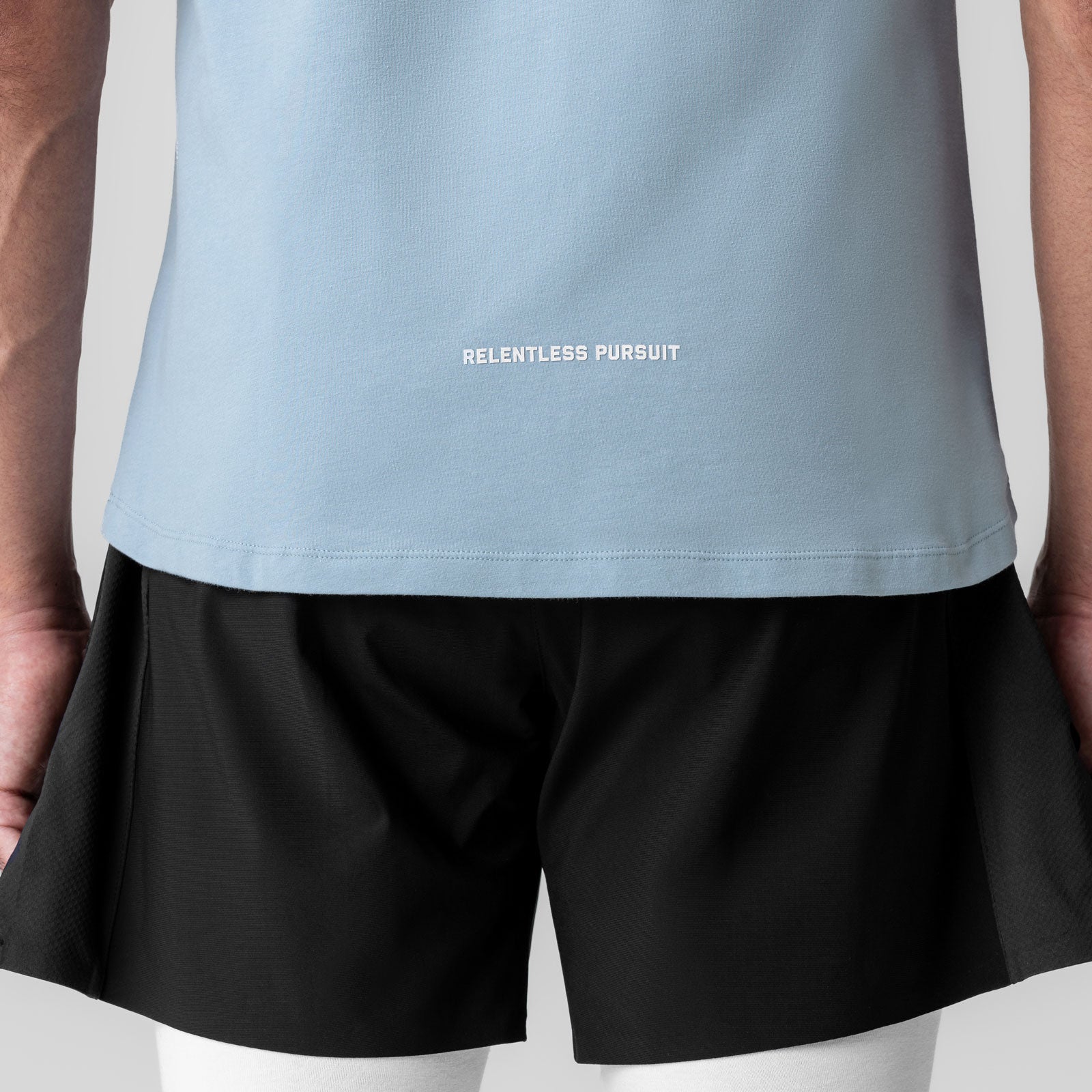 Creora® Cotton Modal Cutoff Tank in light sky worn with black shorts, back view showing 'Relentless Pursuit' text