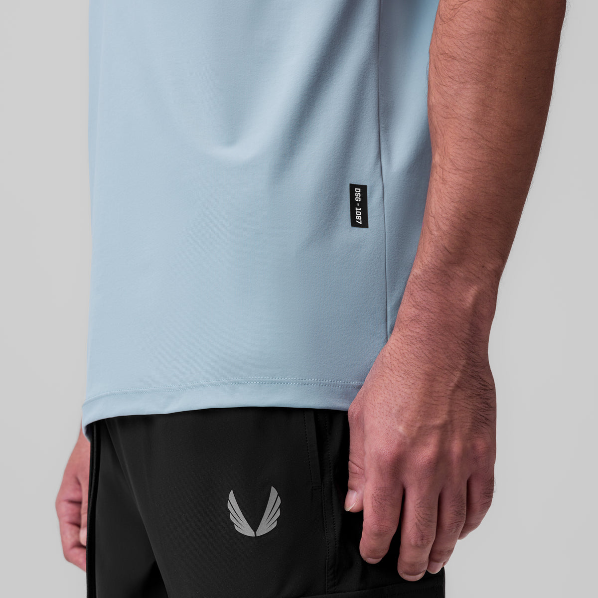 Tetra-Lite Ice Zip Tee in light sky worn with black shorts, side detail view