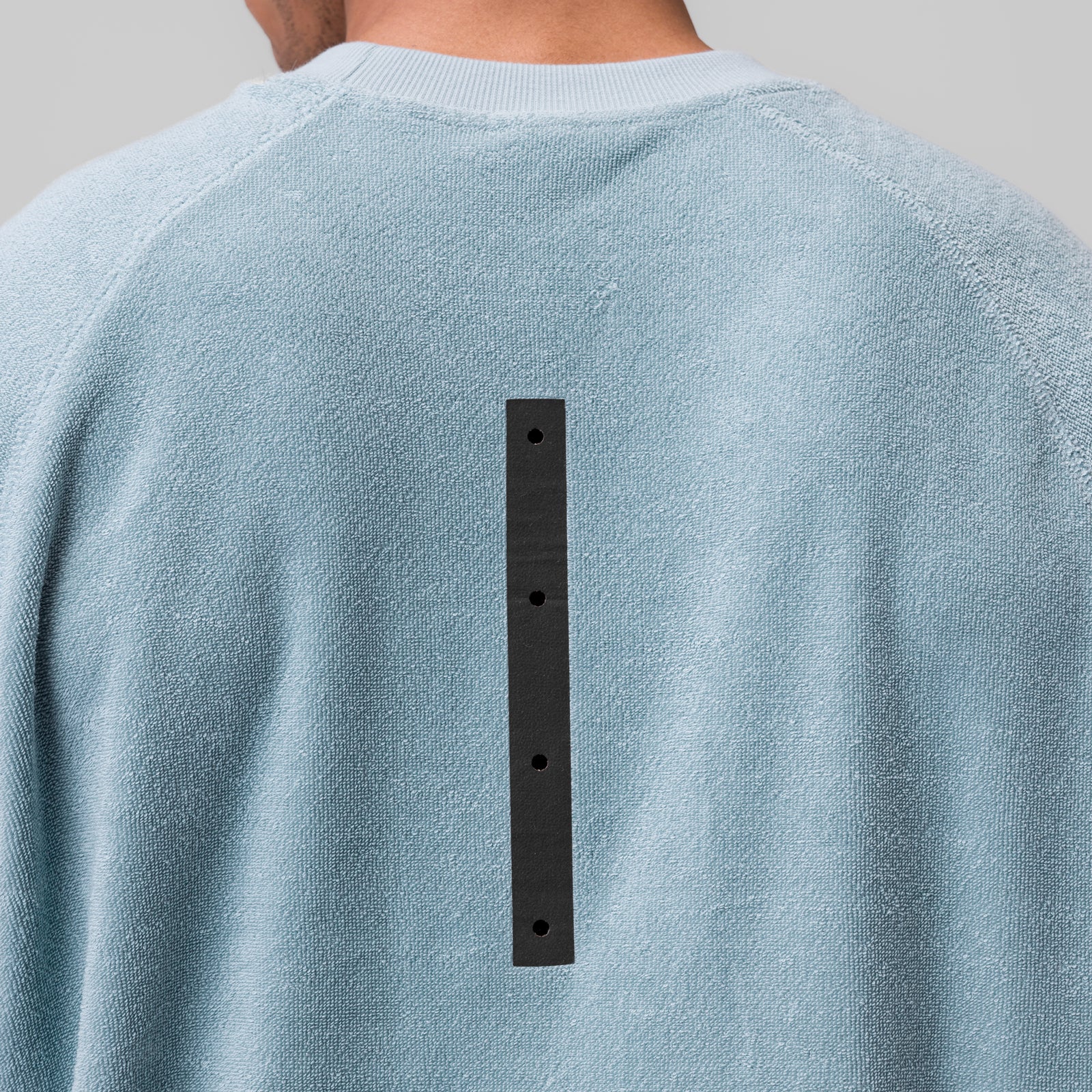 Towel Terry Cutoff in light sky worn by model, back view showing black button detail