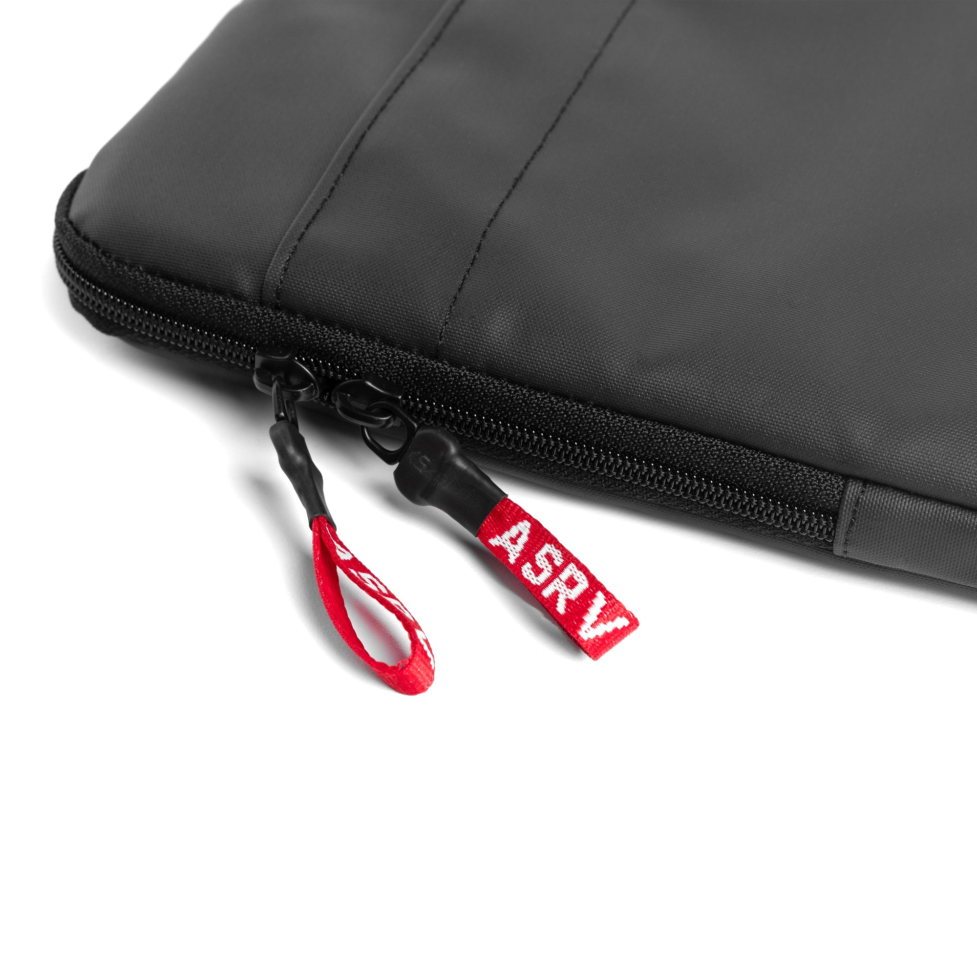 flatlay water resistant padded laptop case in black with red zipper pulls, detail view