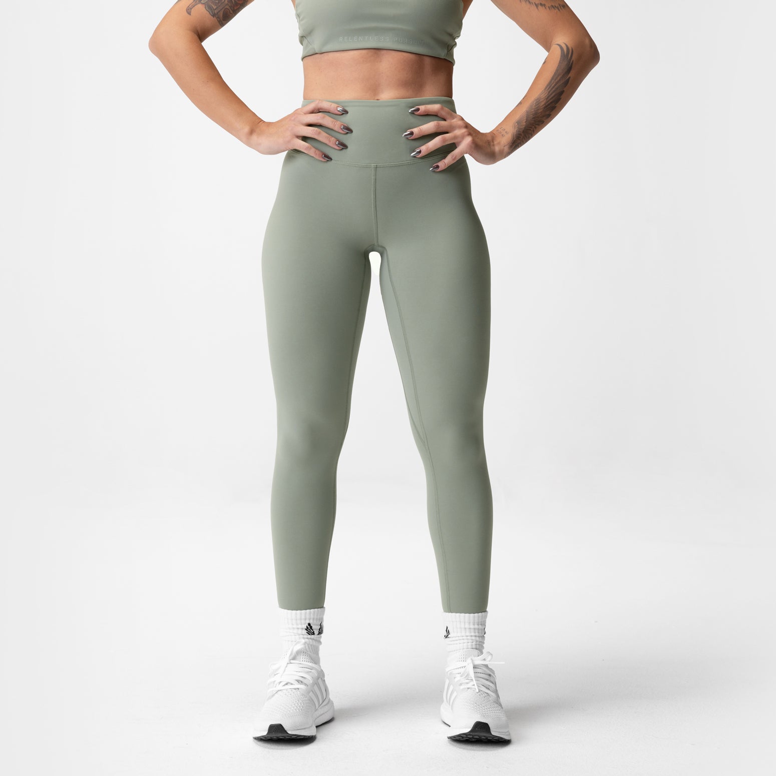 Sage green 7/8 leggings modeled on person wearing white sneakers, front view