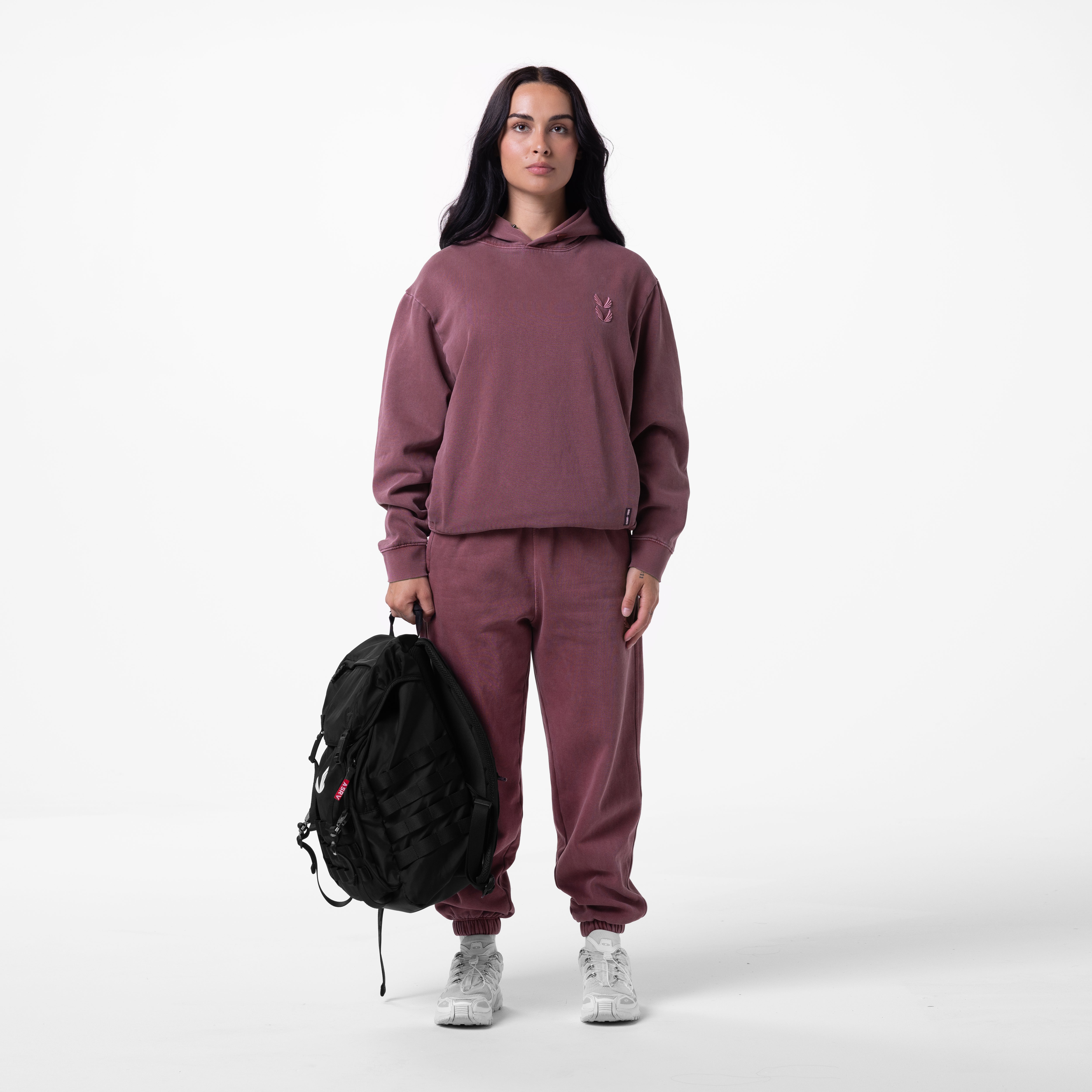 Tech Essential Distressed Hoodie in faded crimson worn with matching joggers, model holding black backpack