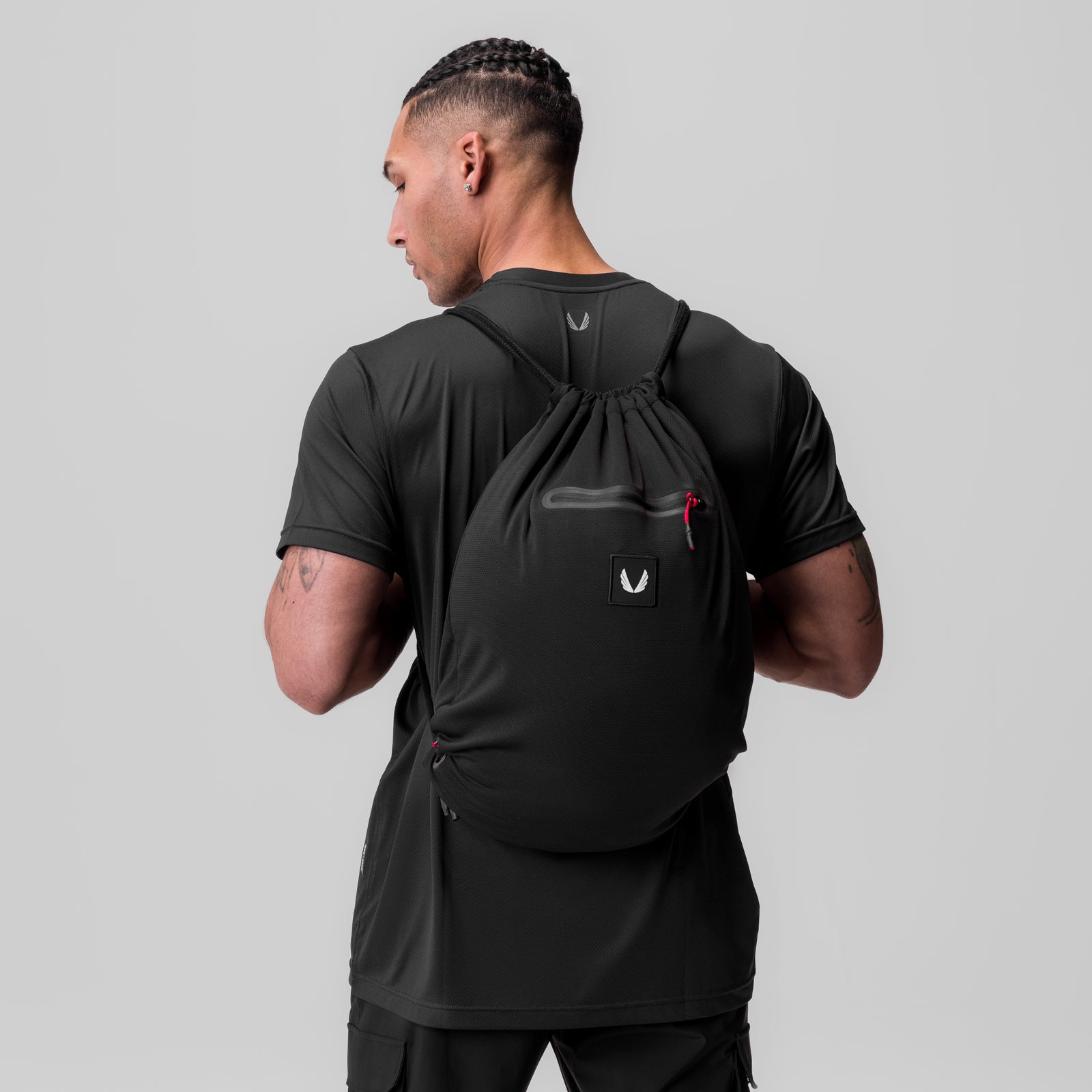 Antibacterial Mesh Drawstring Bag in black, worn on model's back over t-shirt