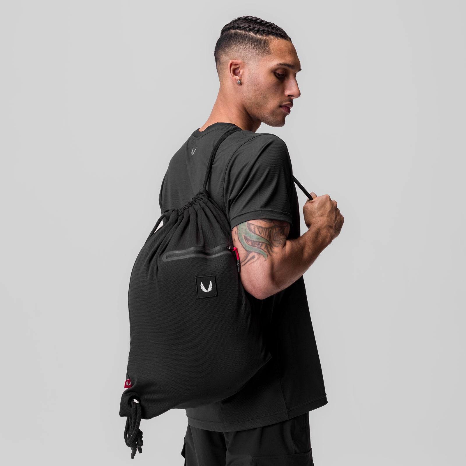 Antibacterial mesh drawstring bag in black, worn on shoulder by model in profile