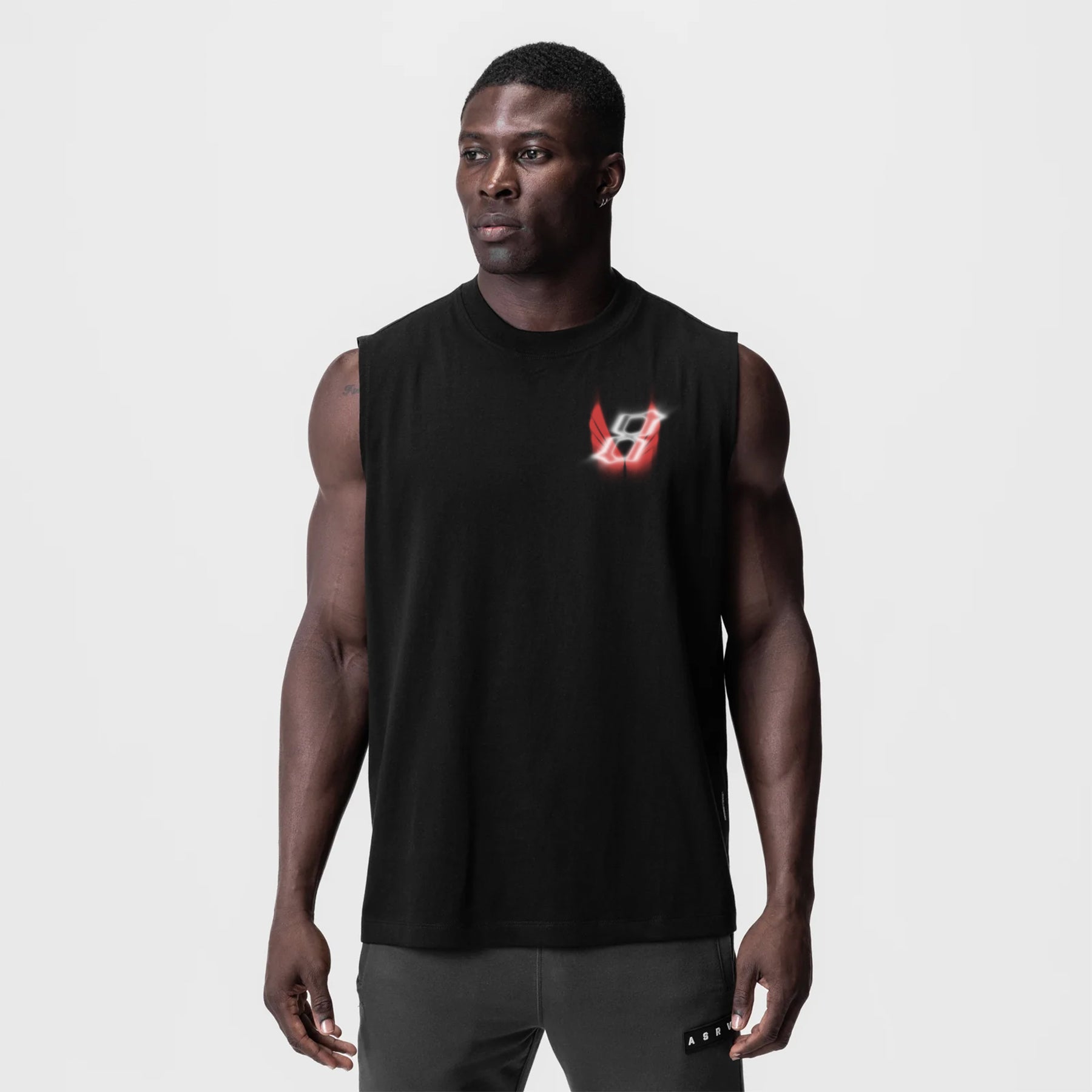 Black Tech Essential Relaxed Cutoff tank top with red logo, worn by model, front view