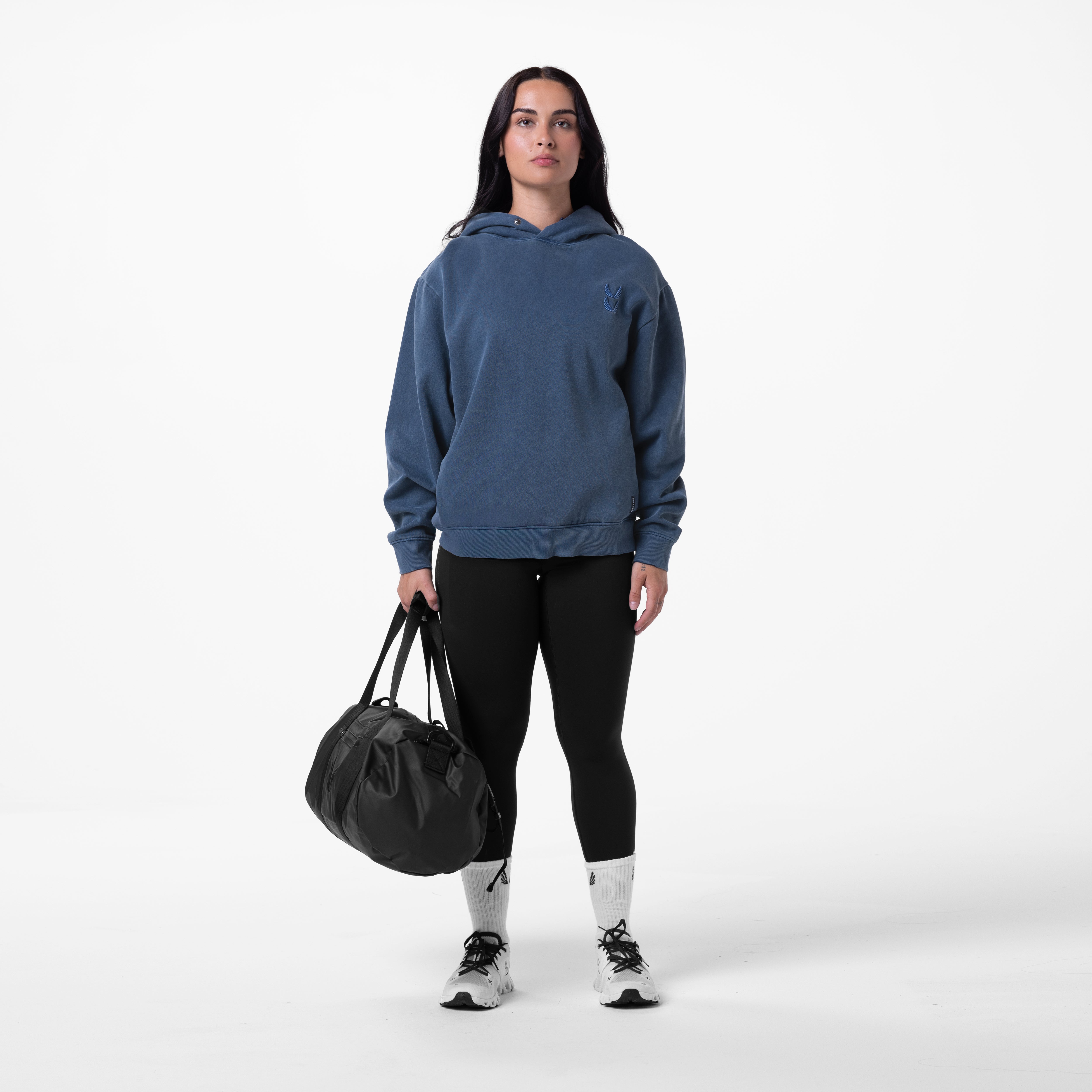 Tech Essential Distressed Hoodie in faded navy worn with black leggings, model holding black duffle bag