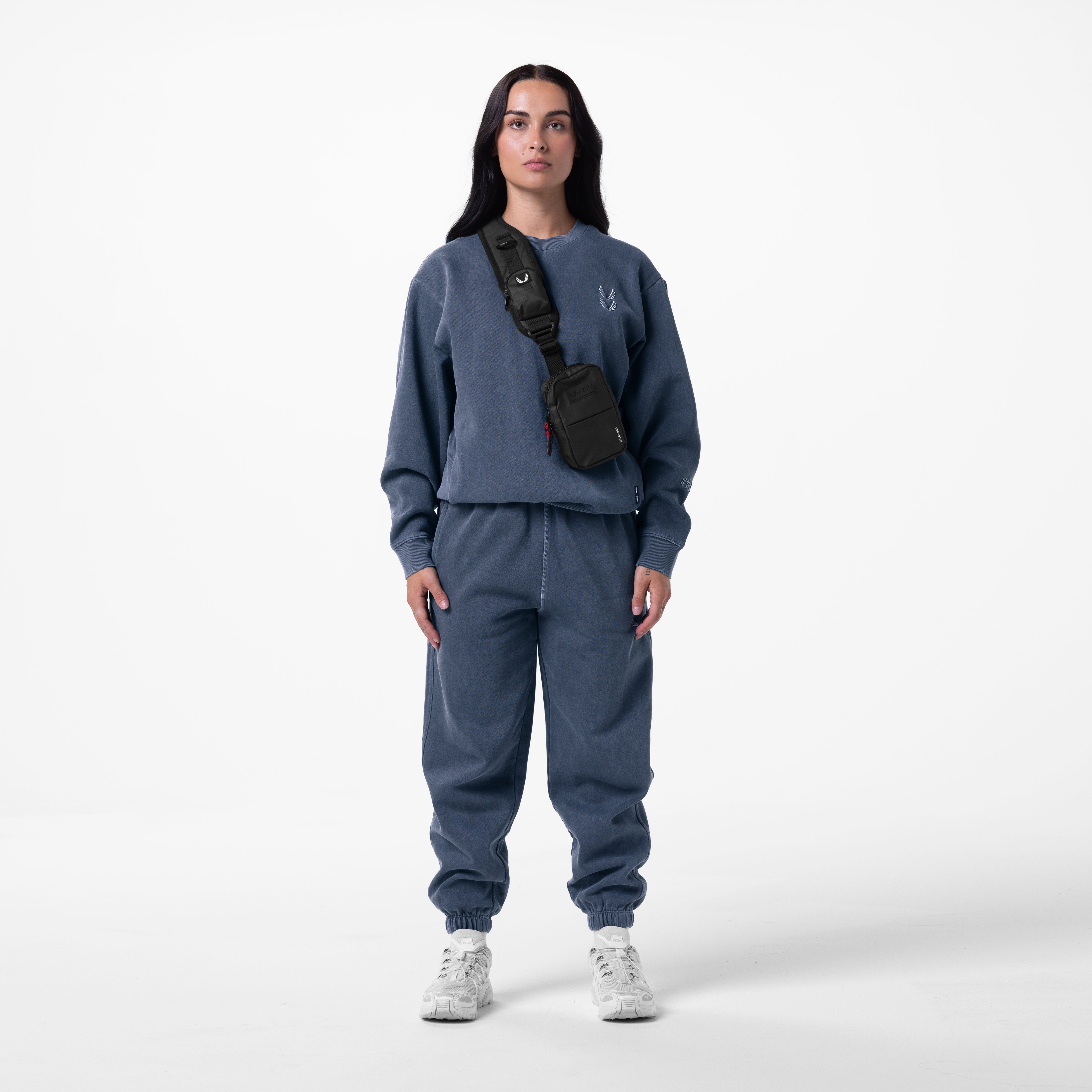 Tech Essential Distressed Crewneck in faded navy worn with matching joggers and black sling bag, front view