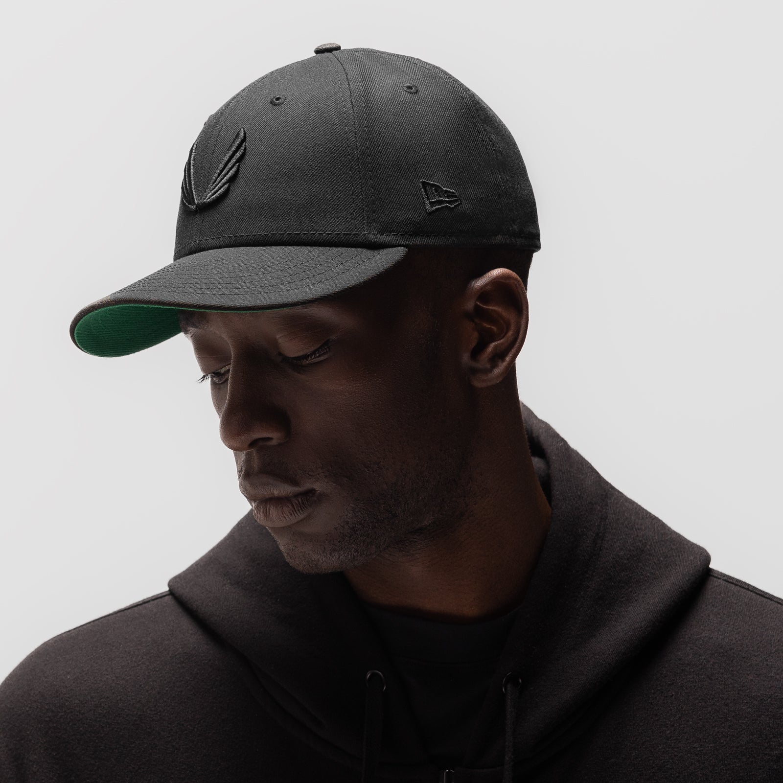 New Era 59Fifty Low Profile Hat in black with wings logo, worn by model in profile view