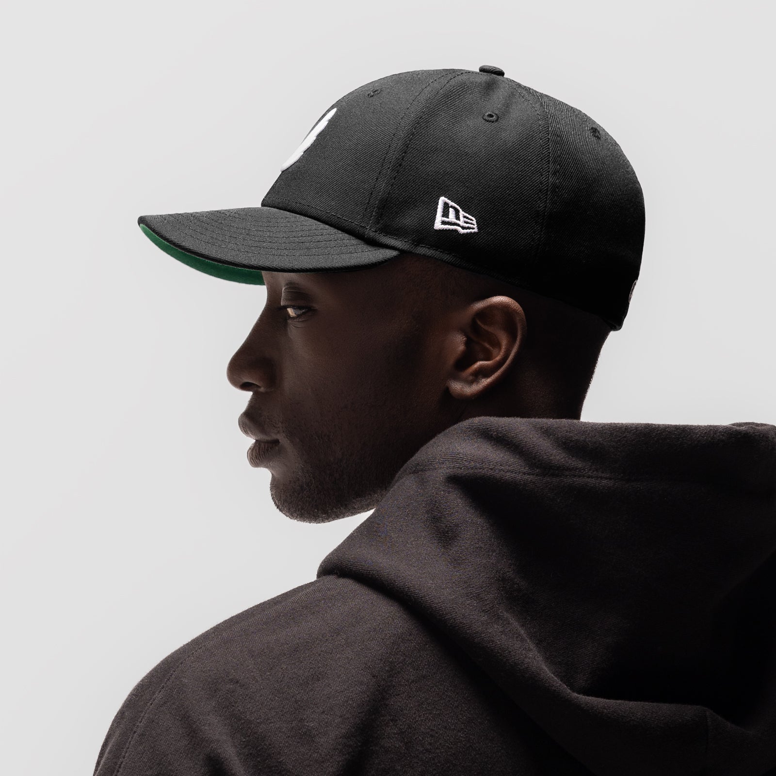 New Era 59Fifty Low Profile Hat in black with white wings logo, worn by model in profile view