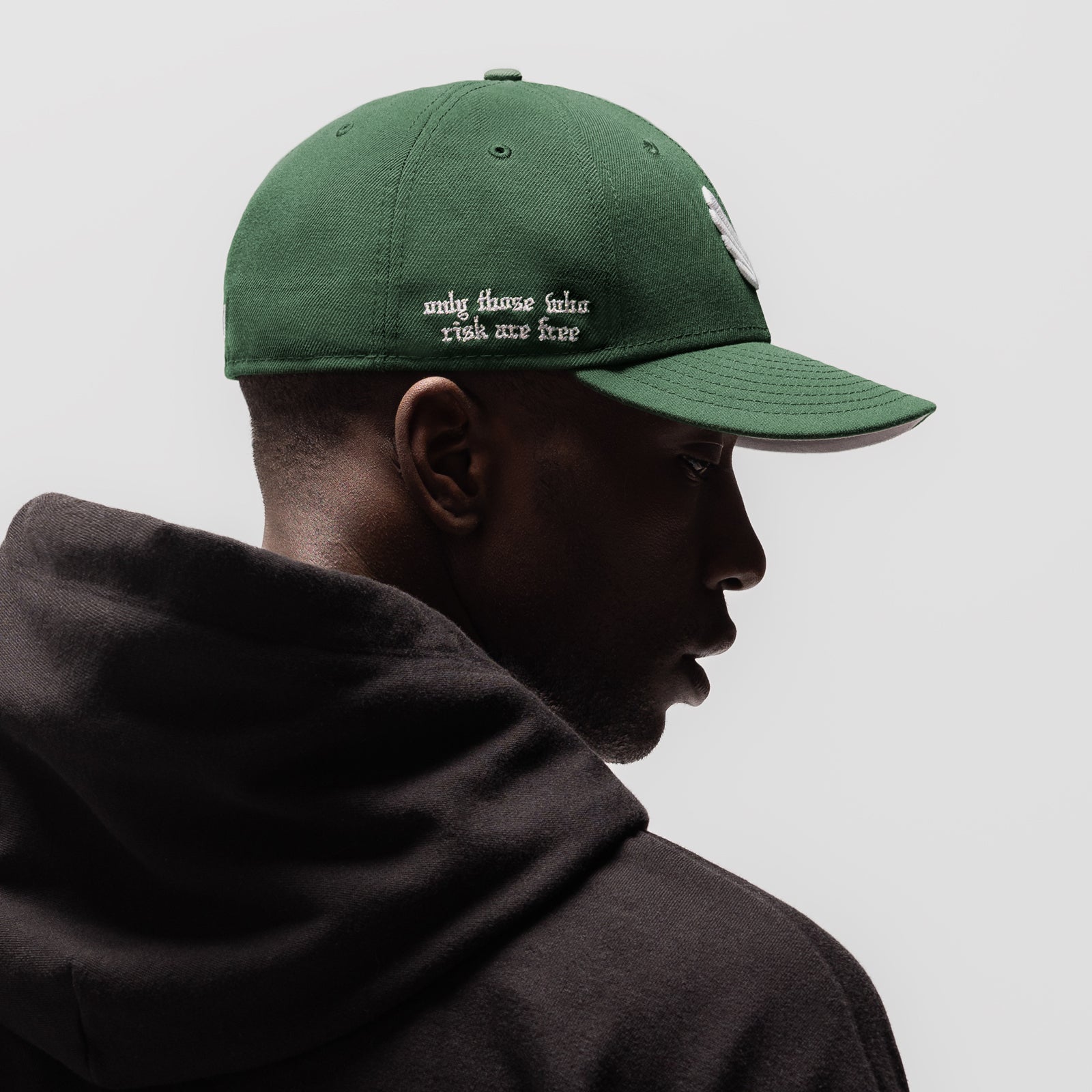 New Era 59Fifty Low Profile Hat in forest green with white wings logo, side profile view on model