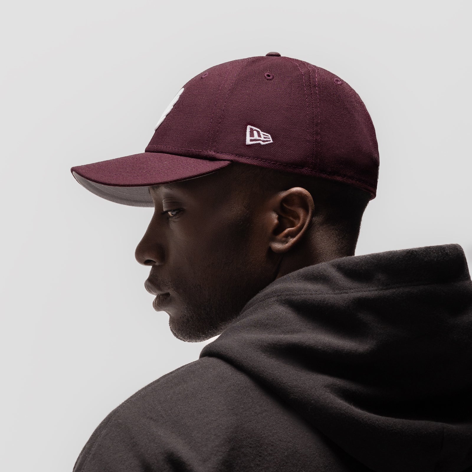 New Era 59Fifty Low Profile Hat in maroon with white logo, worn by model in profile view