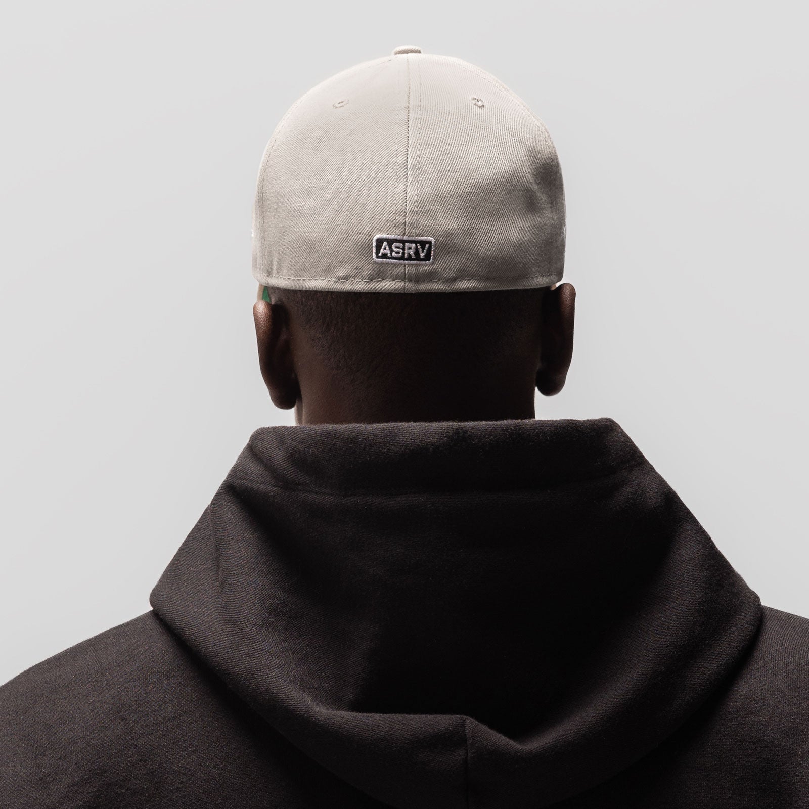 New Era 59Fifty Low Profile Hat in stone and white, worn from back view with black hoodie