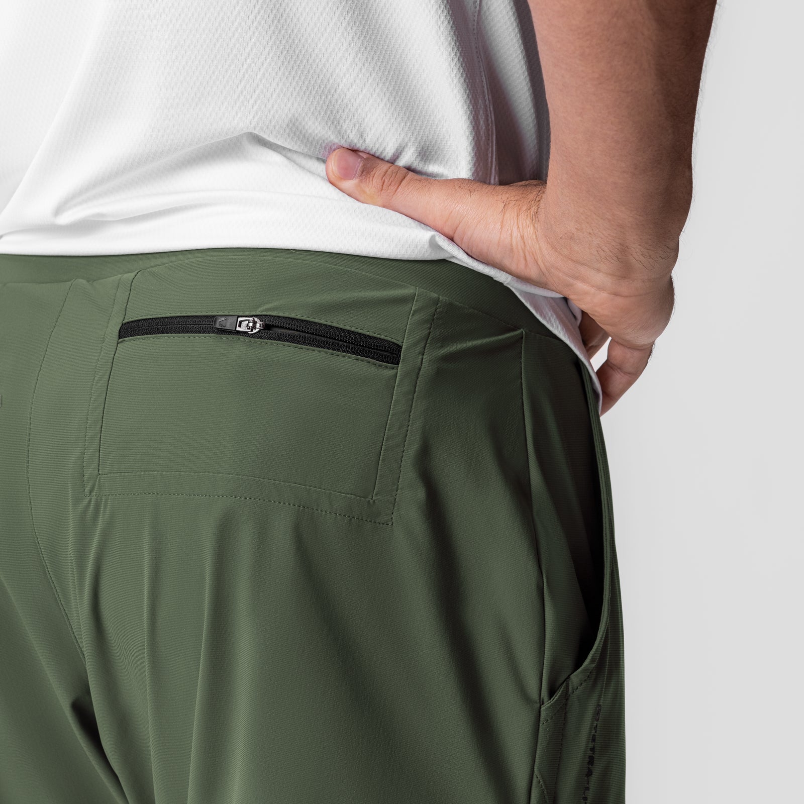 Tetra-Lite 5" Linerless Short in olive, worn with hand in back pocket showing zipper detail