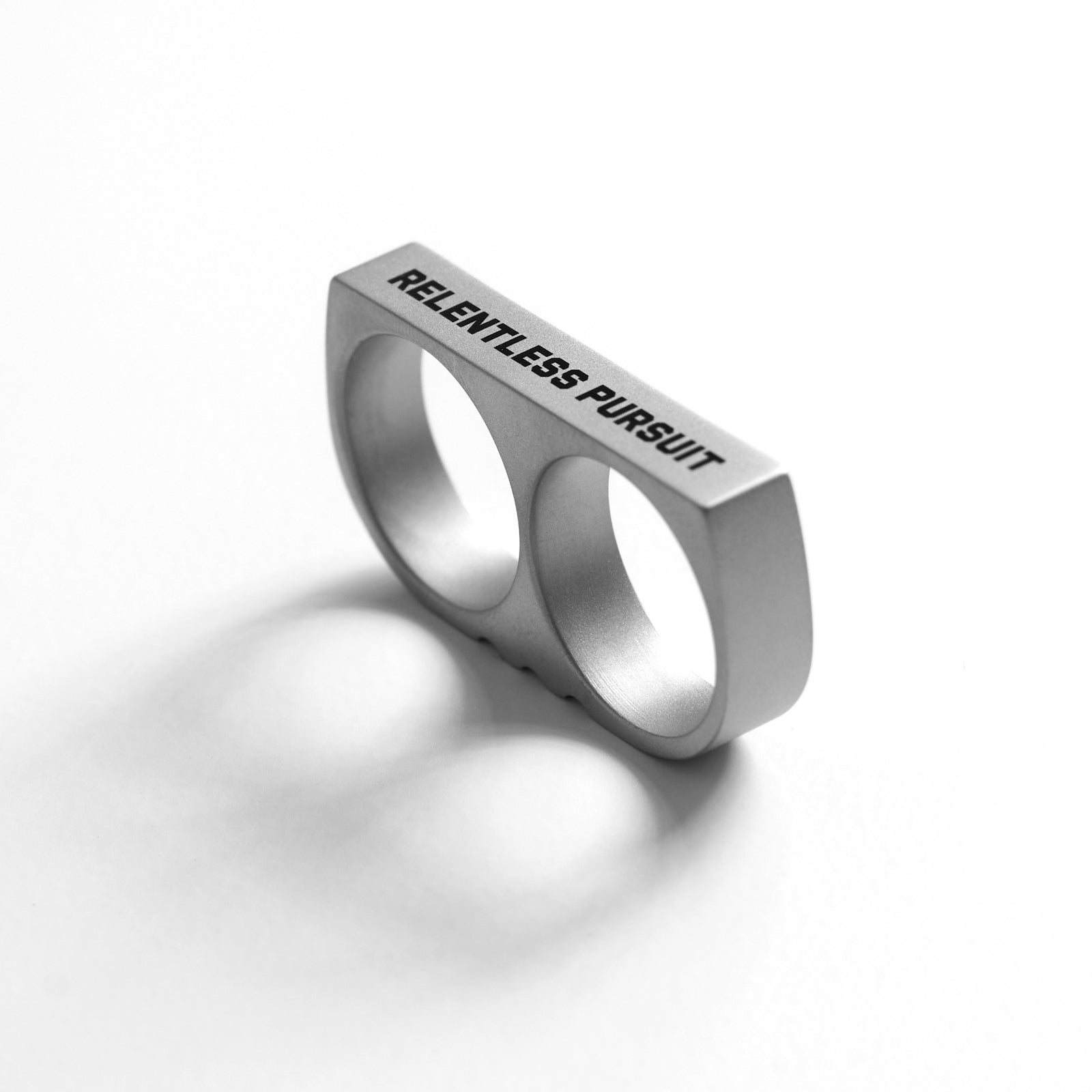 Double Ring stainless steel knuckle ring with "Relentless Pursuit" engraving, silver, angled view