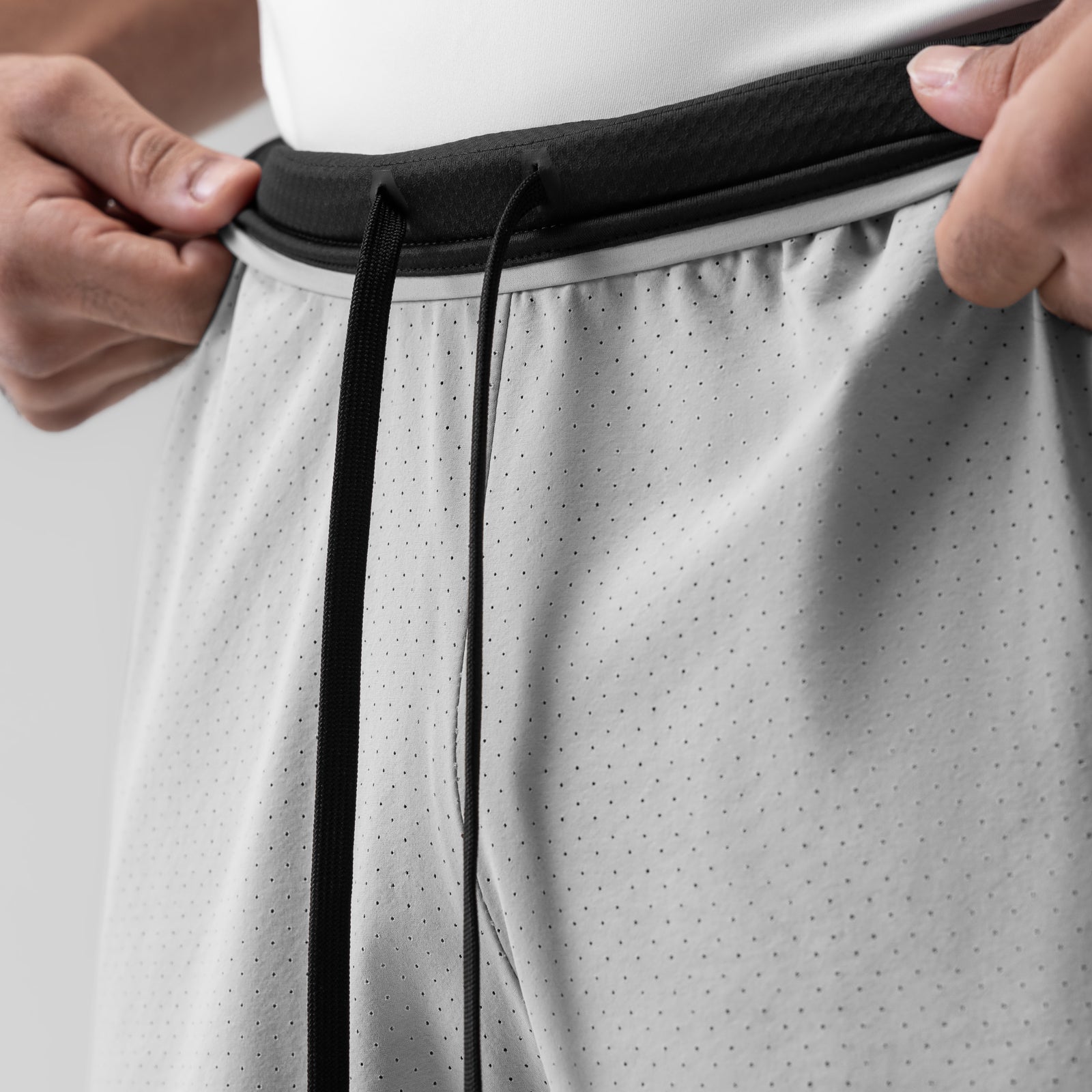 Slate grey 7" liner shorts with black waistband, worn with hands adjusting the drawstring