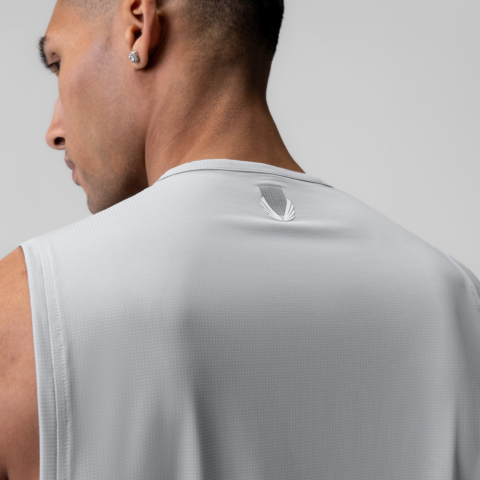 Ice-Skin™ Muscle Tank in slate grey worn by model, back view showing feather logo
