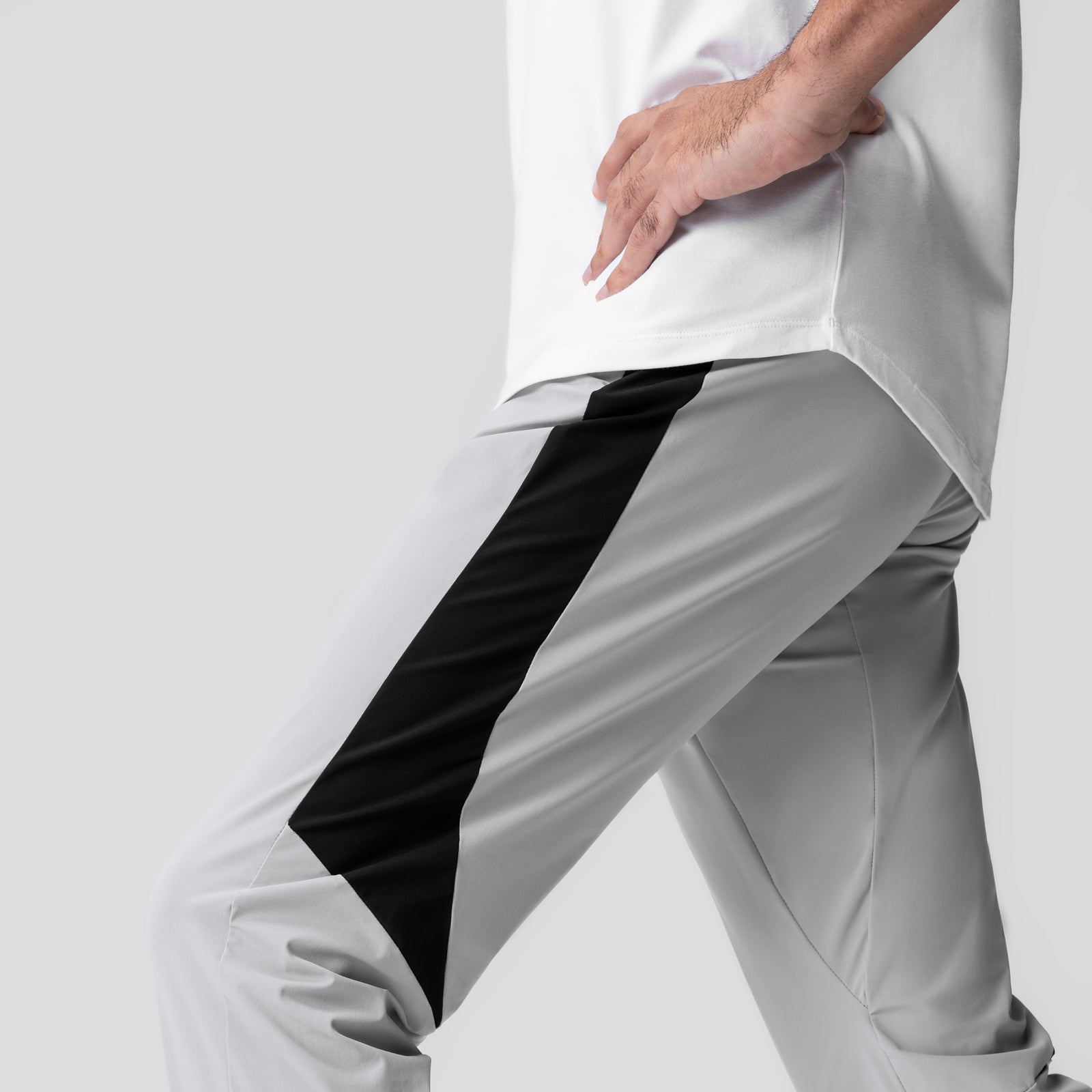 Cuffed training jogger in slate grey with black stripe detail, worn by model showing side view