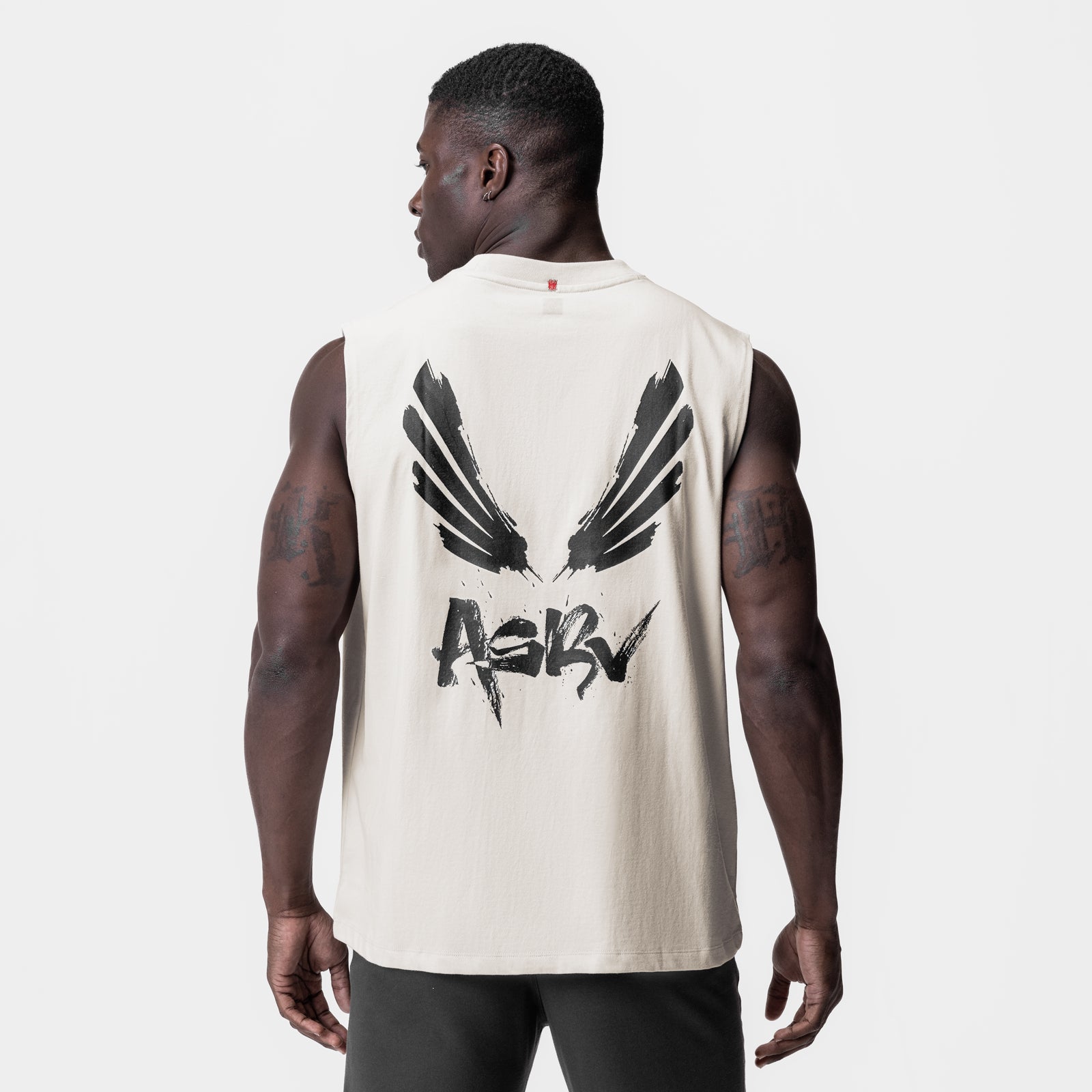 Tech Essential Relaxed Cutoff tank in stone with brush wings graphic, back view on model