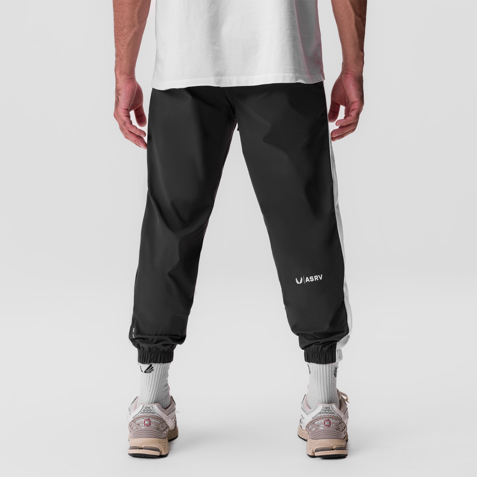 Black ripstop oversized track pant worn by model, back view with white socks and sneakers