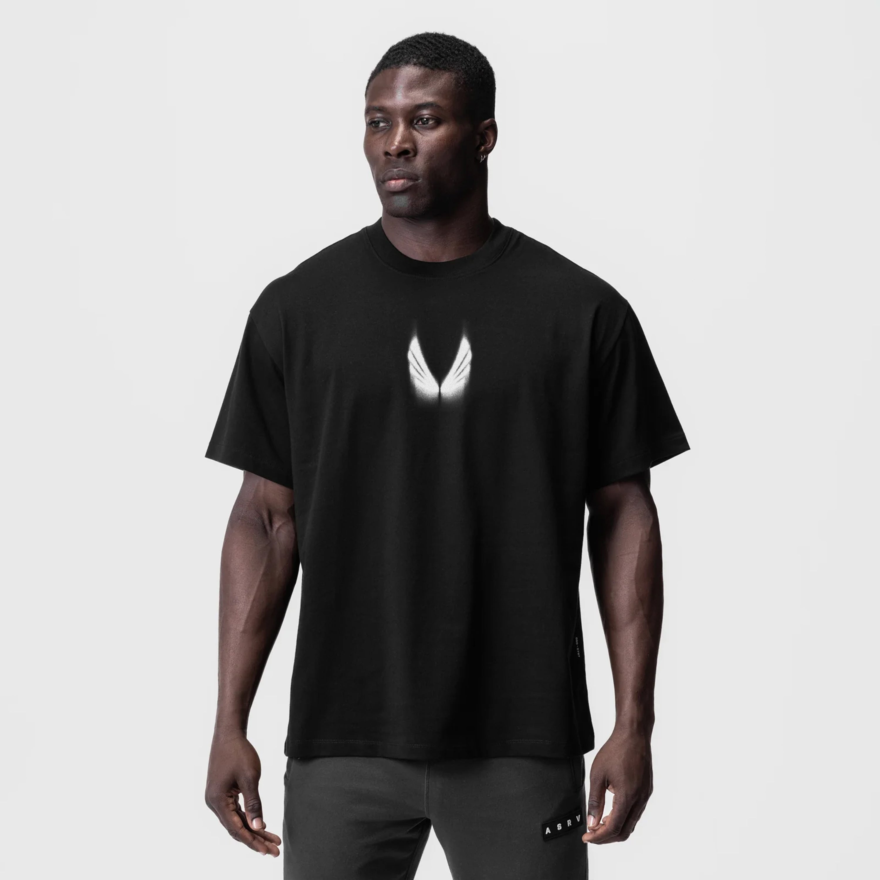 Black Tech Essential Relaxed Tee with white wing logo, worn by model, front view