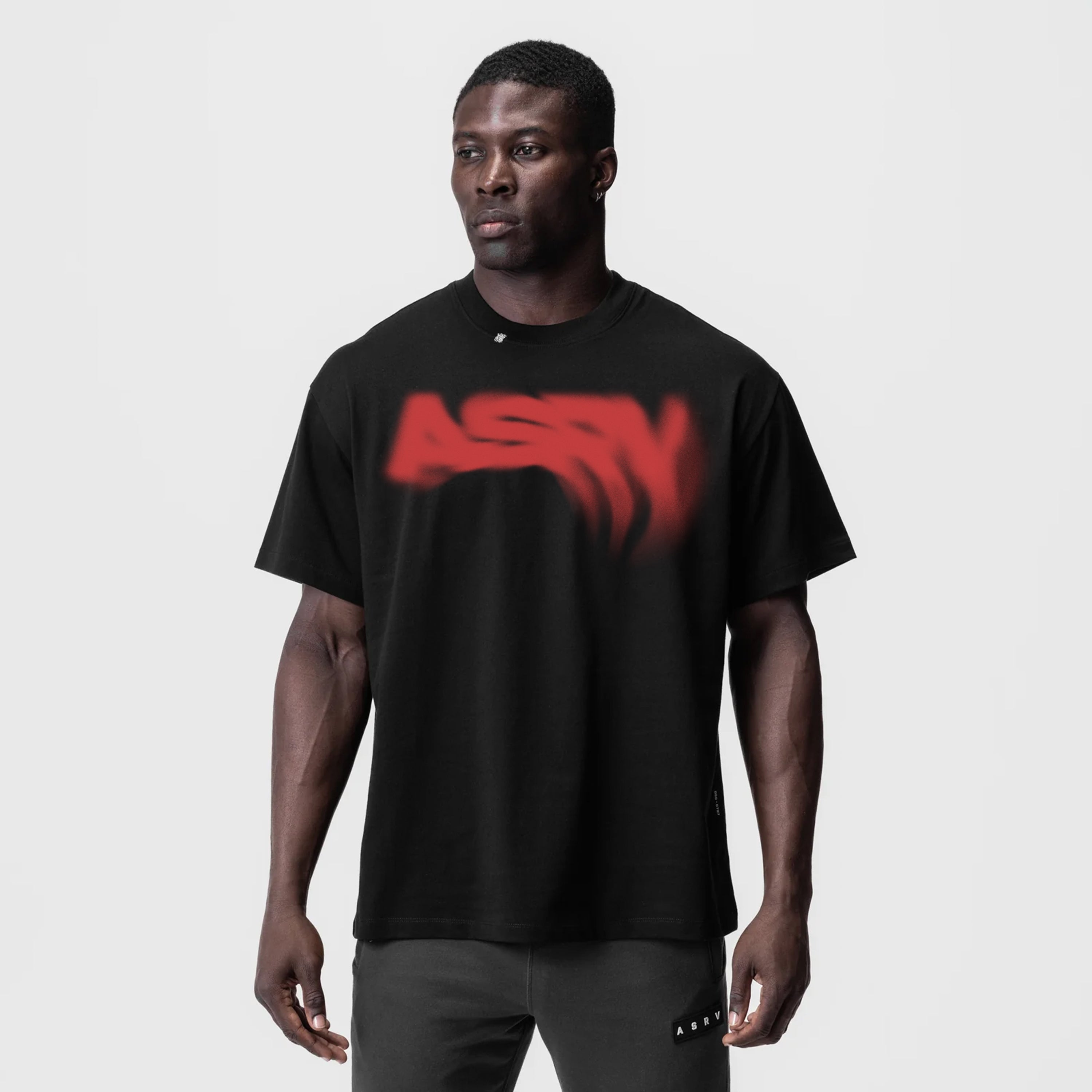 Black Tech Essential Relaxed Tee with red blurred graphic design, worn by model, front view