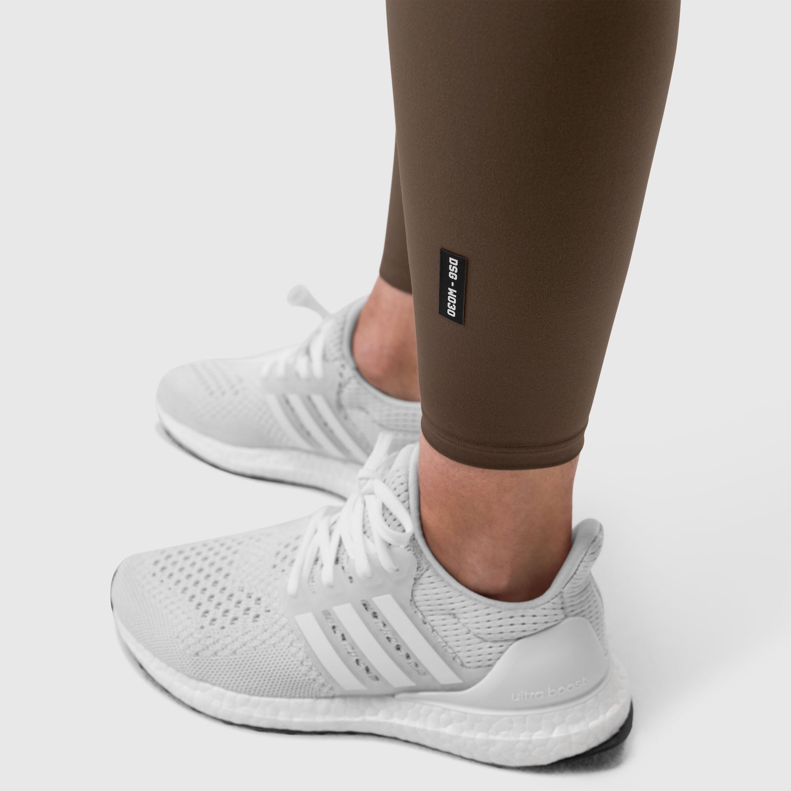 W030 LYCRA® 3-in-1 Legging in Dark Earth worn with white sneakers, ankle detail view