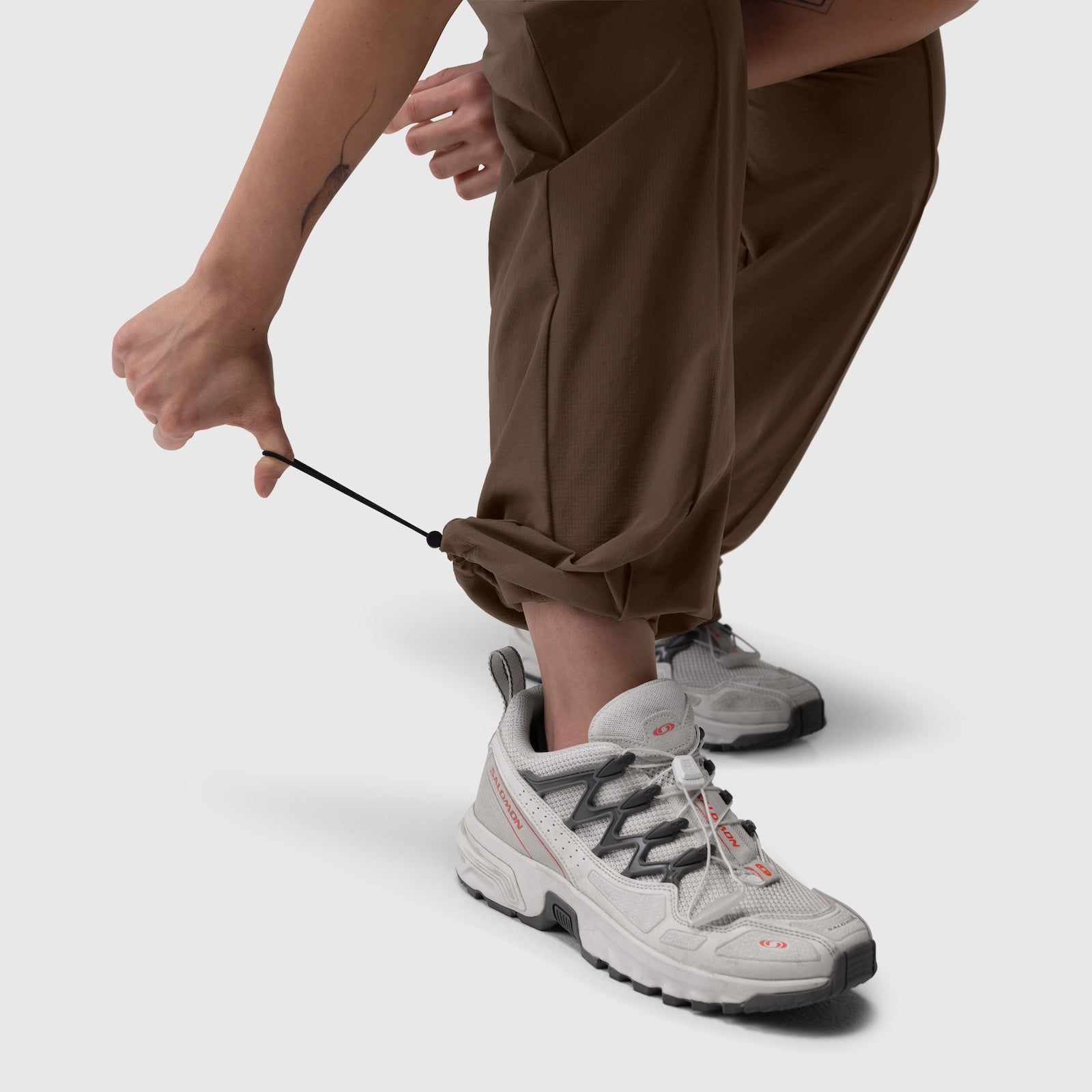 W036 Ripstop Relaxed Track Pant in Dark Earth, worn with white sneakers, detail of drawstring adjustment