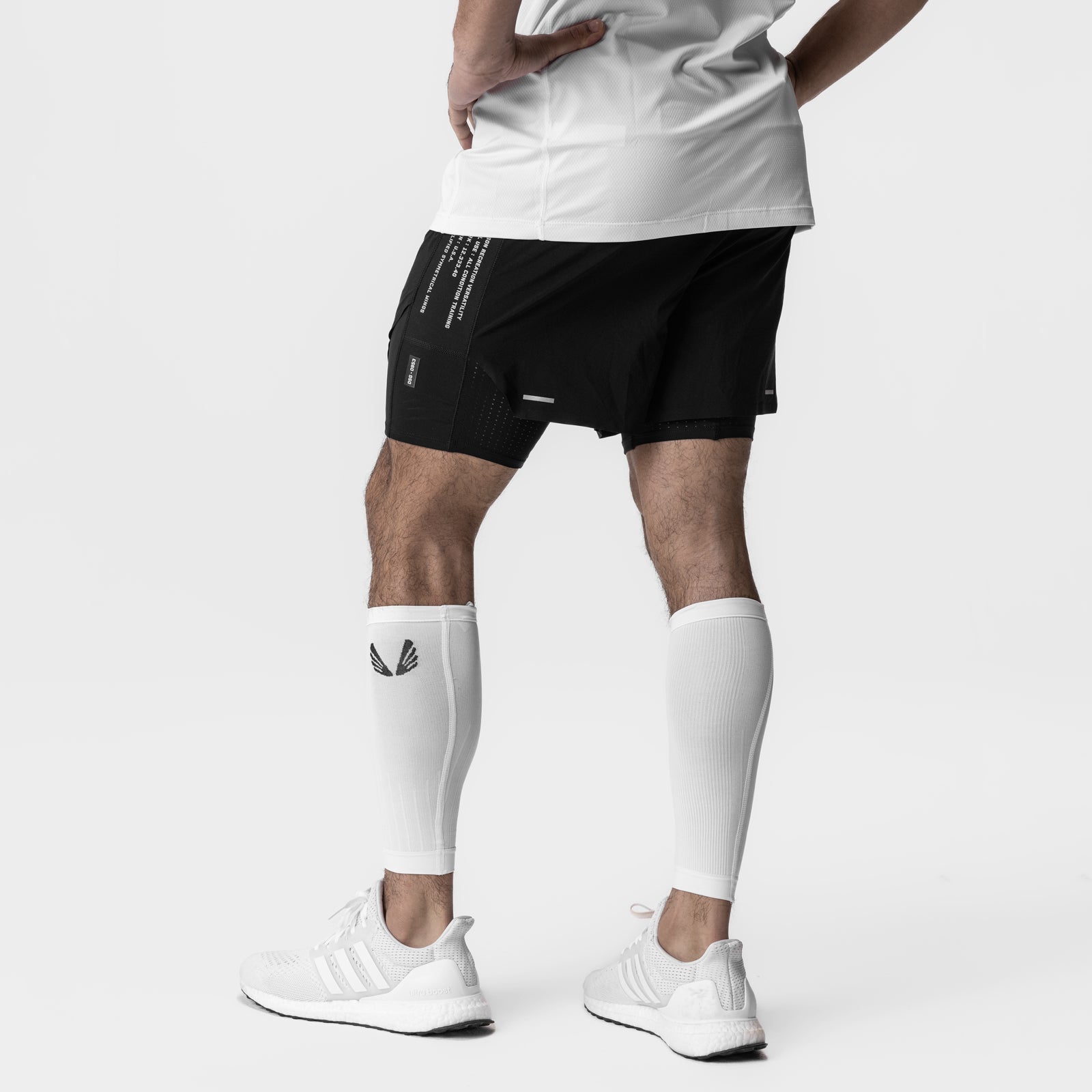 White body-mapped calf sleeve worn on model's leg, paired with black shorts and white sneakers