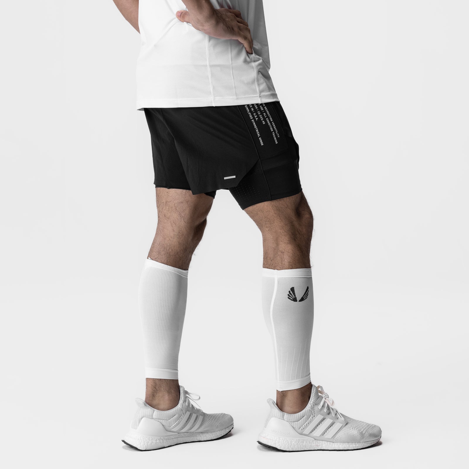 Body-Mapped Calf Sleeve in white, worn on model's legs with black shorts and white sneakers