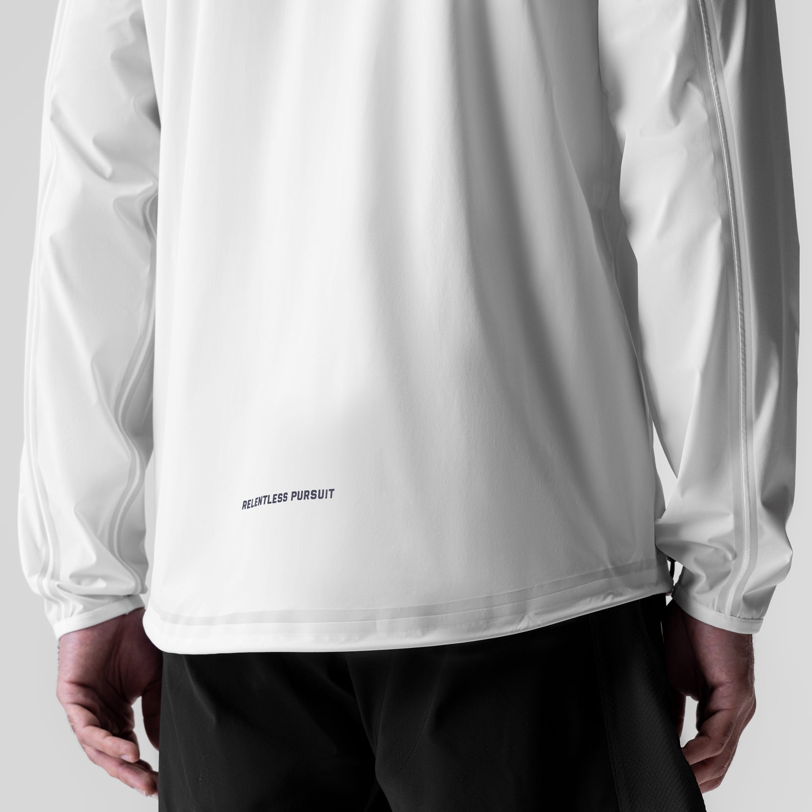 White Aerotex™ Lightweight Windbreaker worn by model, back view showing 'Relentless Pursuit' text