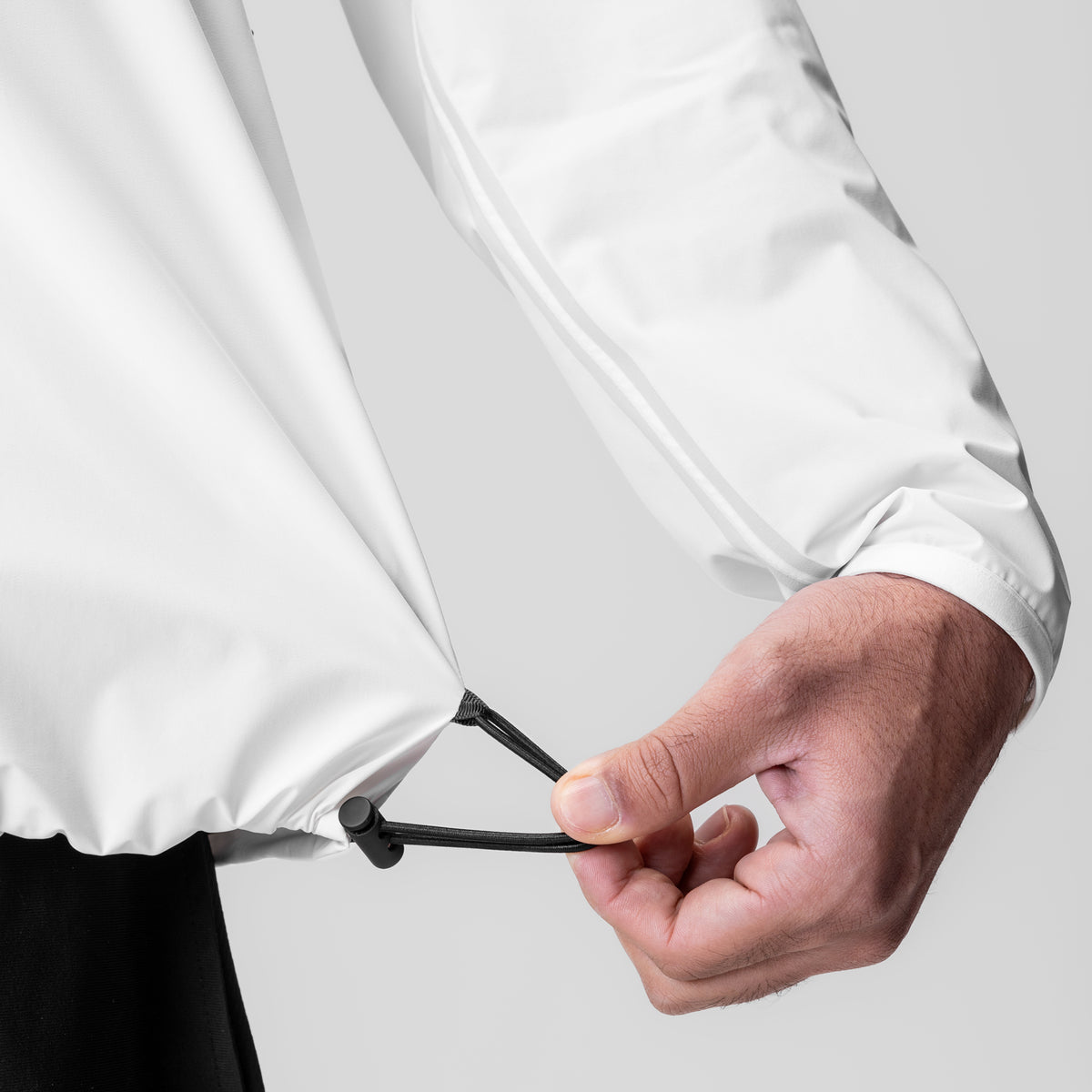 Aerotex Lightweight Windbreaker in white, model wearing jacket with hand adjusting drawstring