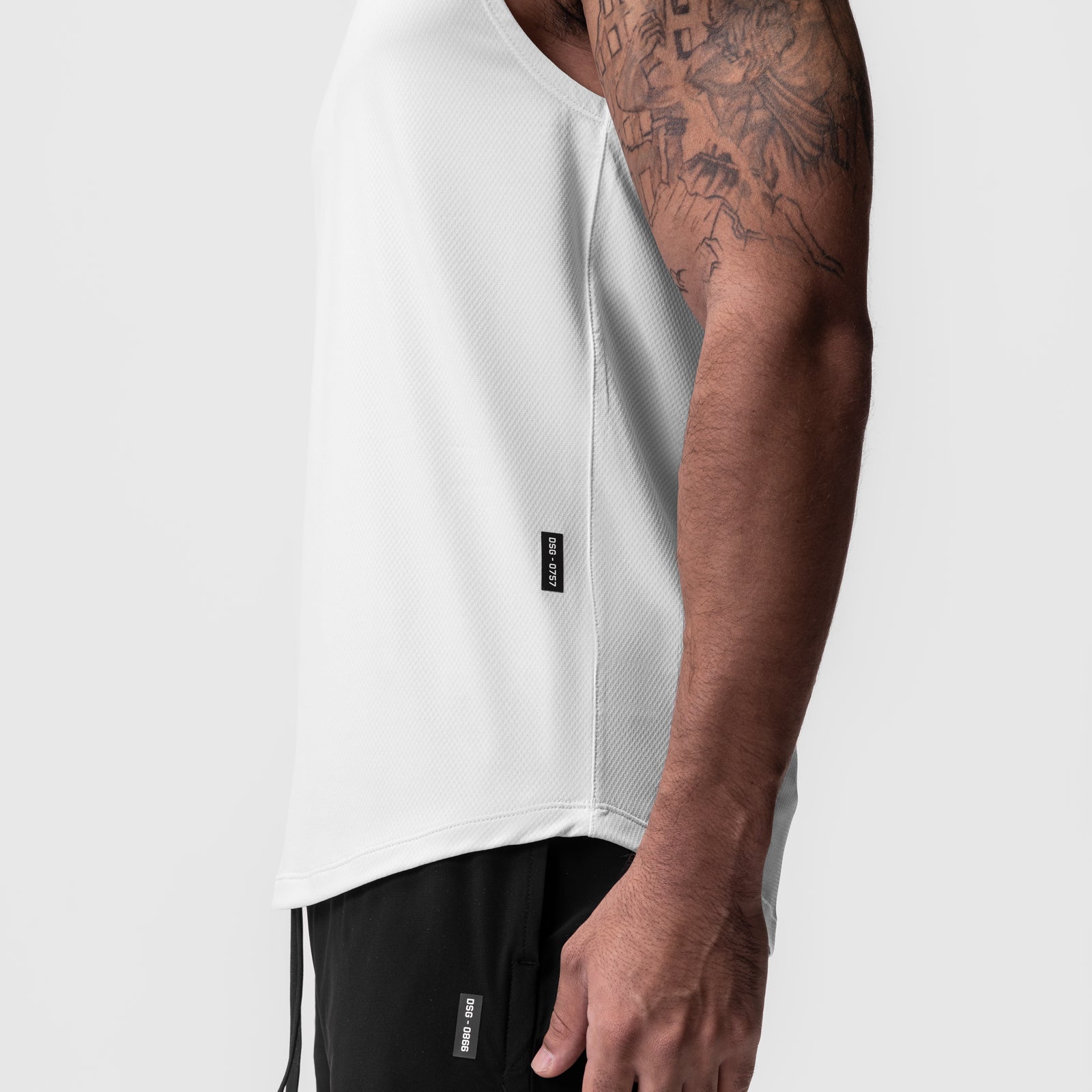 AeroSilver® Cutoff Tank in white, side view on model with black shorts