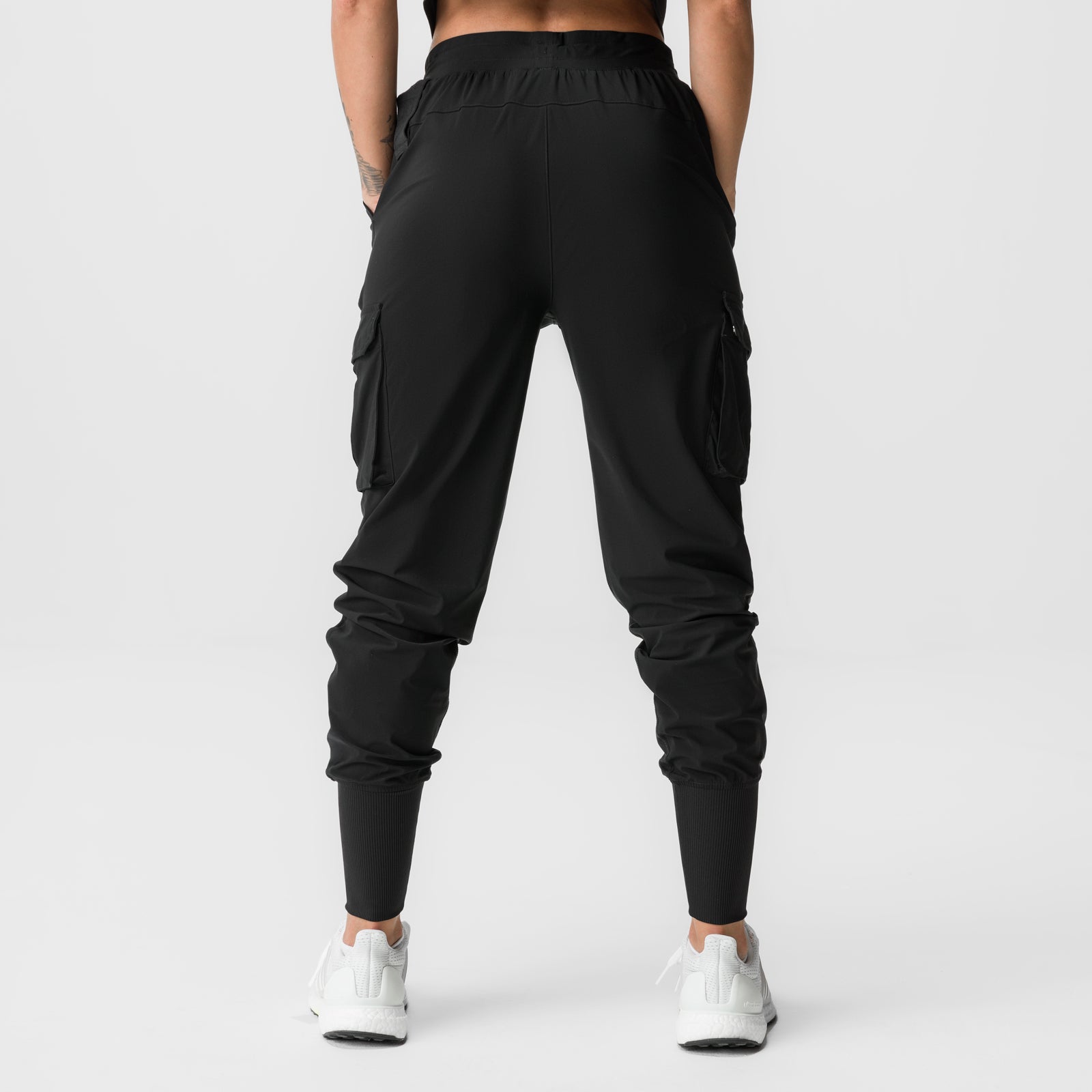 Black cargo jogger with high ribbed cuffs and side pockets, back view on model with white sneakers