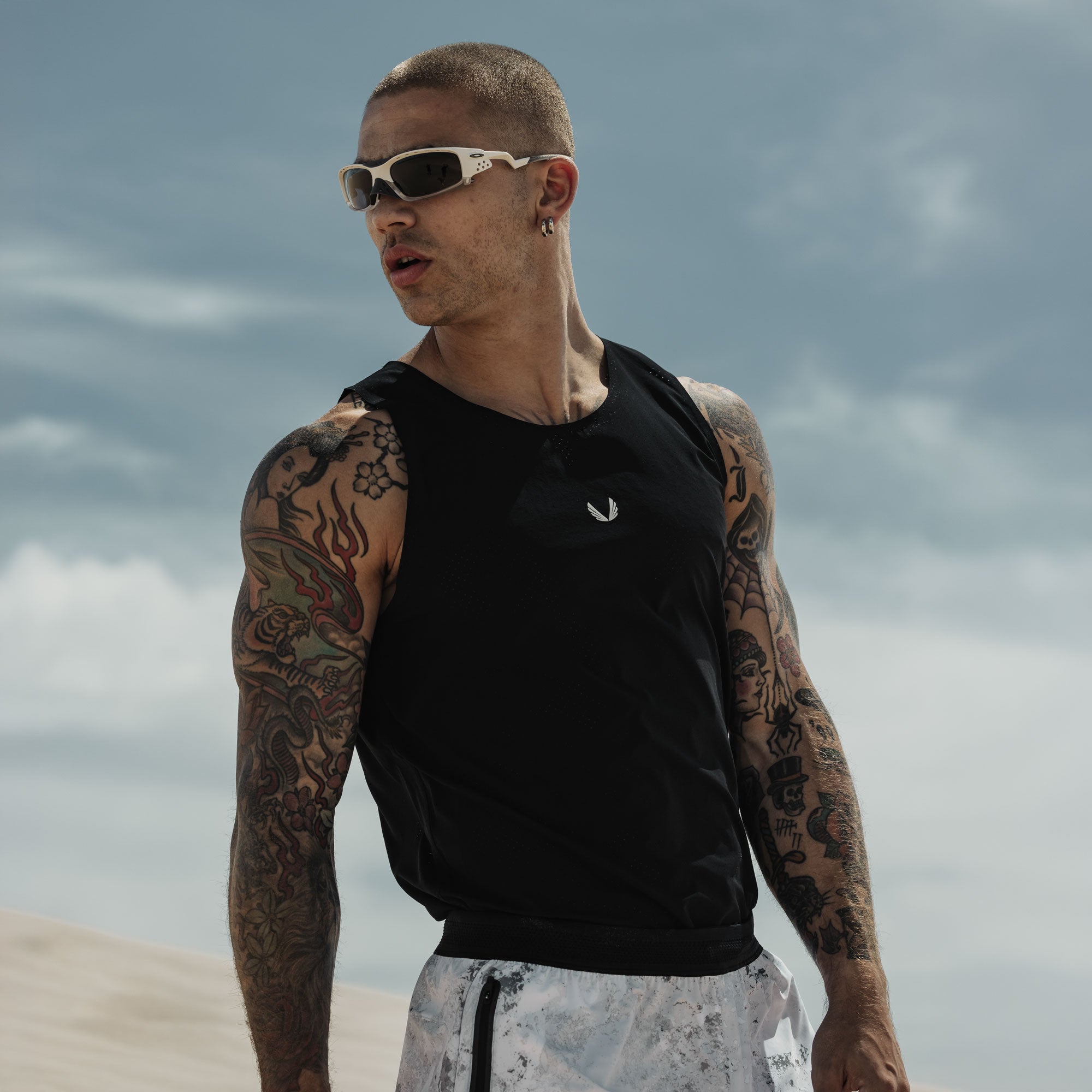 Black Aerotex Perforated Run Tank worn by model at beach, front view